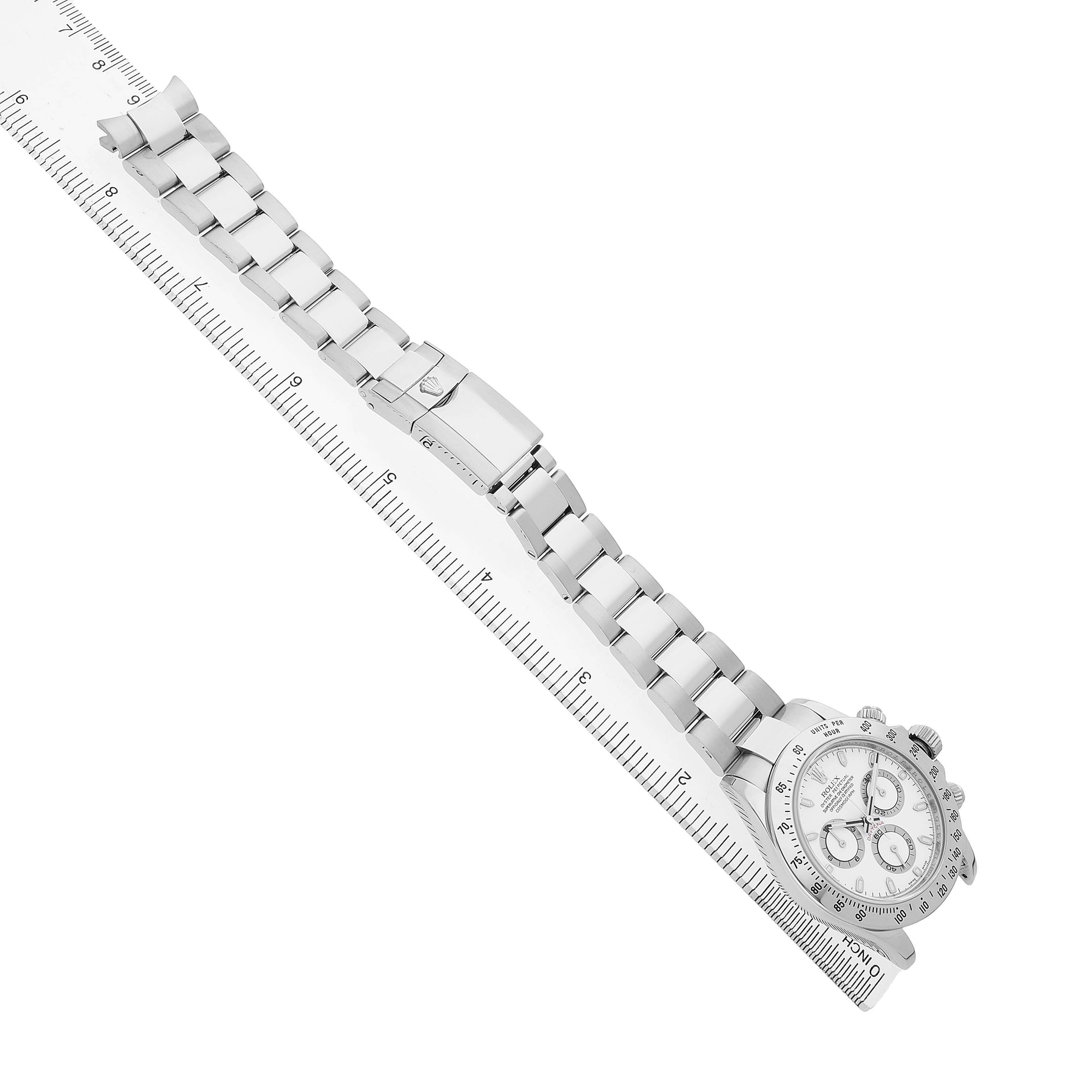 The Rolex Daytona 116520 Men's Stainless Steel White Dial watch is displayed side-on, highlighting the bracelet, clasp, and part of the dial against a ruler.