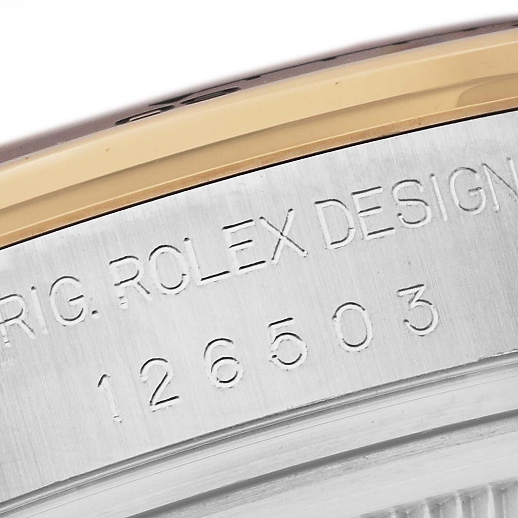 The image shows a close-up of the edge of a Rolex Daytona 126503 Men's Steel and Gold (two tone) Black Dial 126503 Men's Steel and Gold (two tone) Black Dial watch case, highlighting the "Rolex Design" engraving and model number 126503.