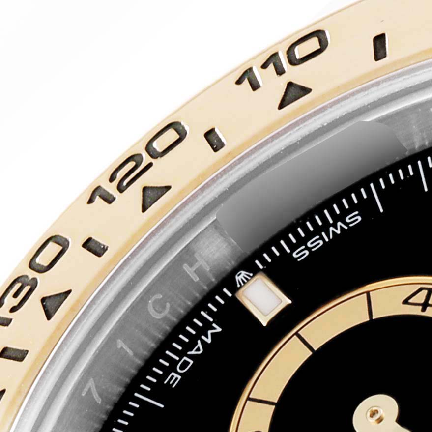 This close-up angle of a Rolex Daytona 126503 Men's Steel and Gold (two tone) Black Dial 126503 Men's Steel and Gold (two tone) Black Dial watch shows the bezel with numerical markers and a portion of the dial with "Swiss Made."