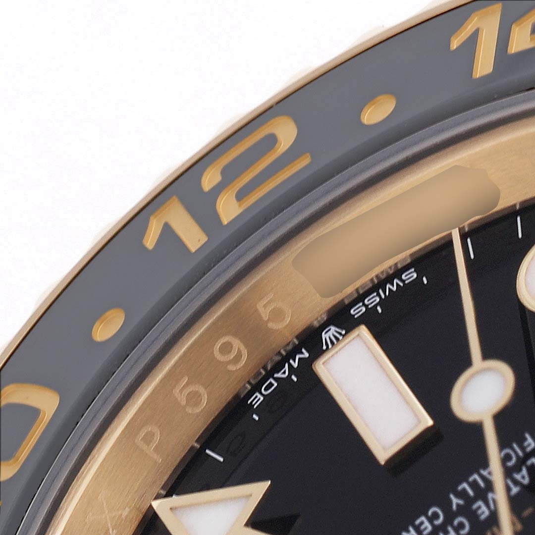 The image shows a close-up of the bezel, hour markers, and part of the dial of a Rolex GMT-Master 126718GRNR Men's Yellow Gold Black Dial watch.