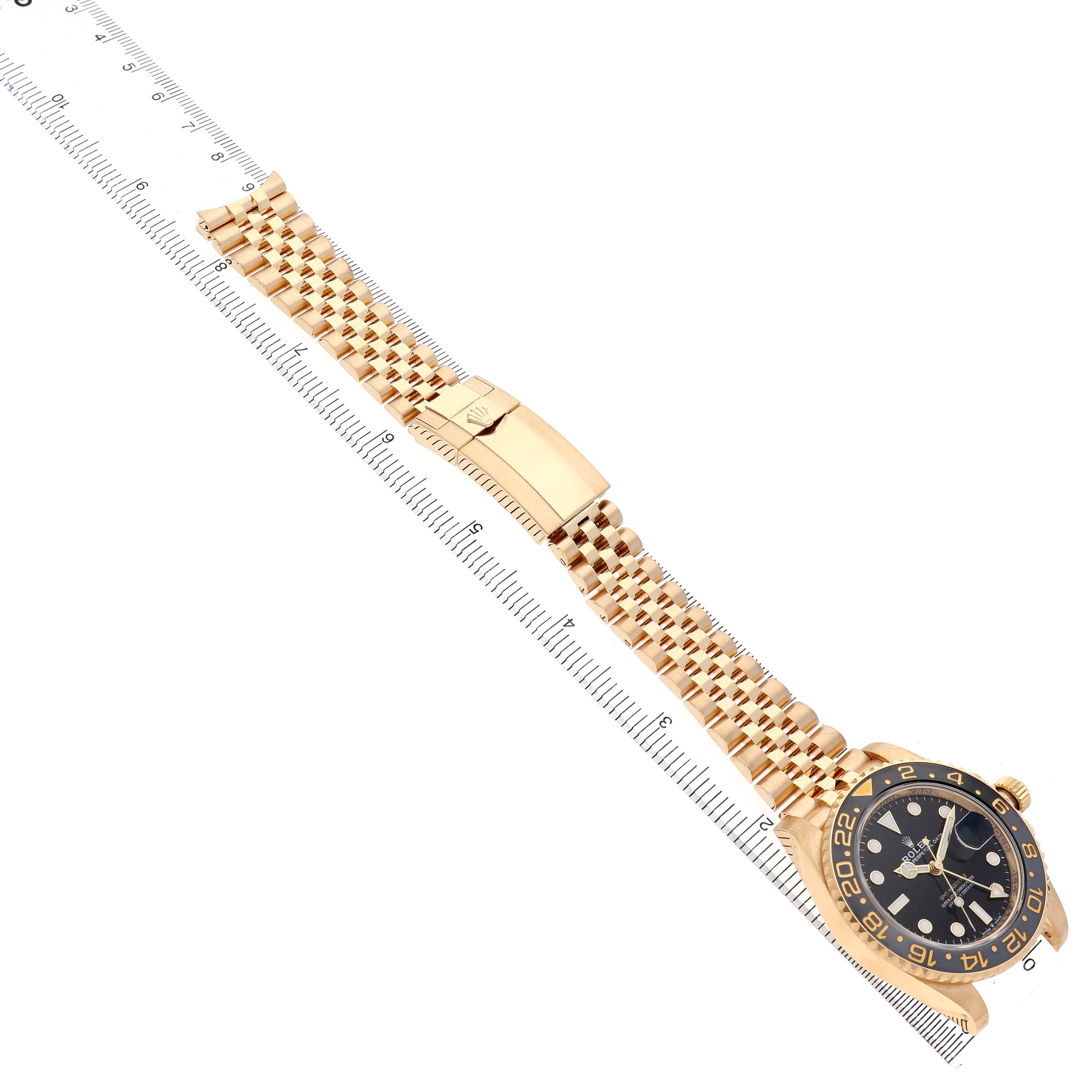 The Rolex GMT-Master 126718GRNR Men's Yellow Gold Black Dial watch is shown diagonally from above, displaying the bracelet, clasp, and face.
