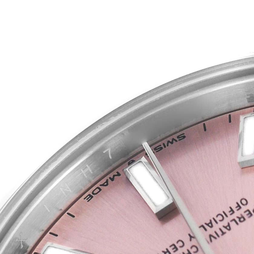 This close-up of the Rolex Mid-Size 277200 Women's Stainless Steel Pink Dial watch shows part of the pink dial, silver hands, indices, and the edge of the bezel.