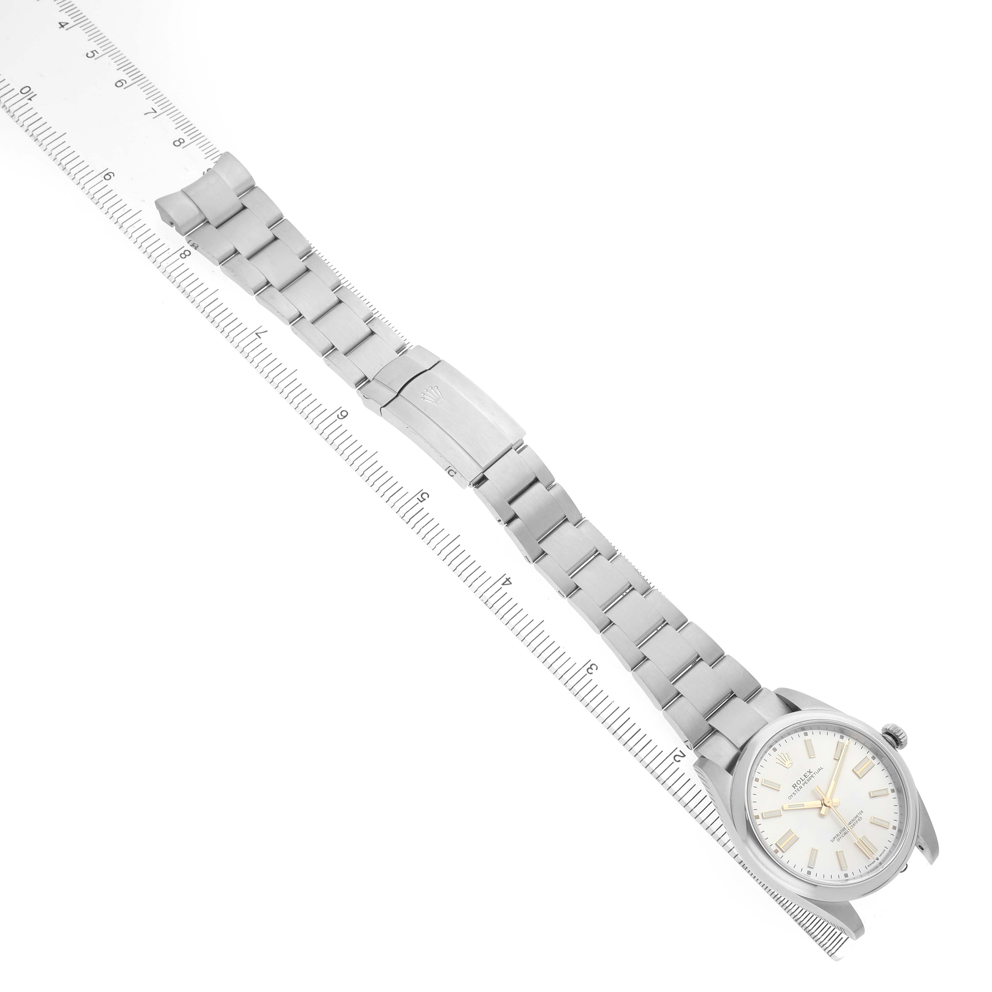 The image shows the Rolex Oyster Perpetual 124300 Men's Stainless Steel Silver Dial watch laid flat with the bracelet extended alongside a ruler.