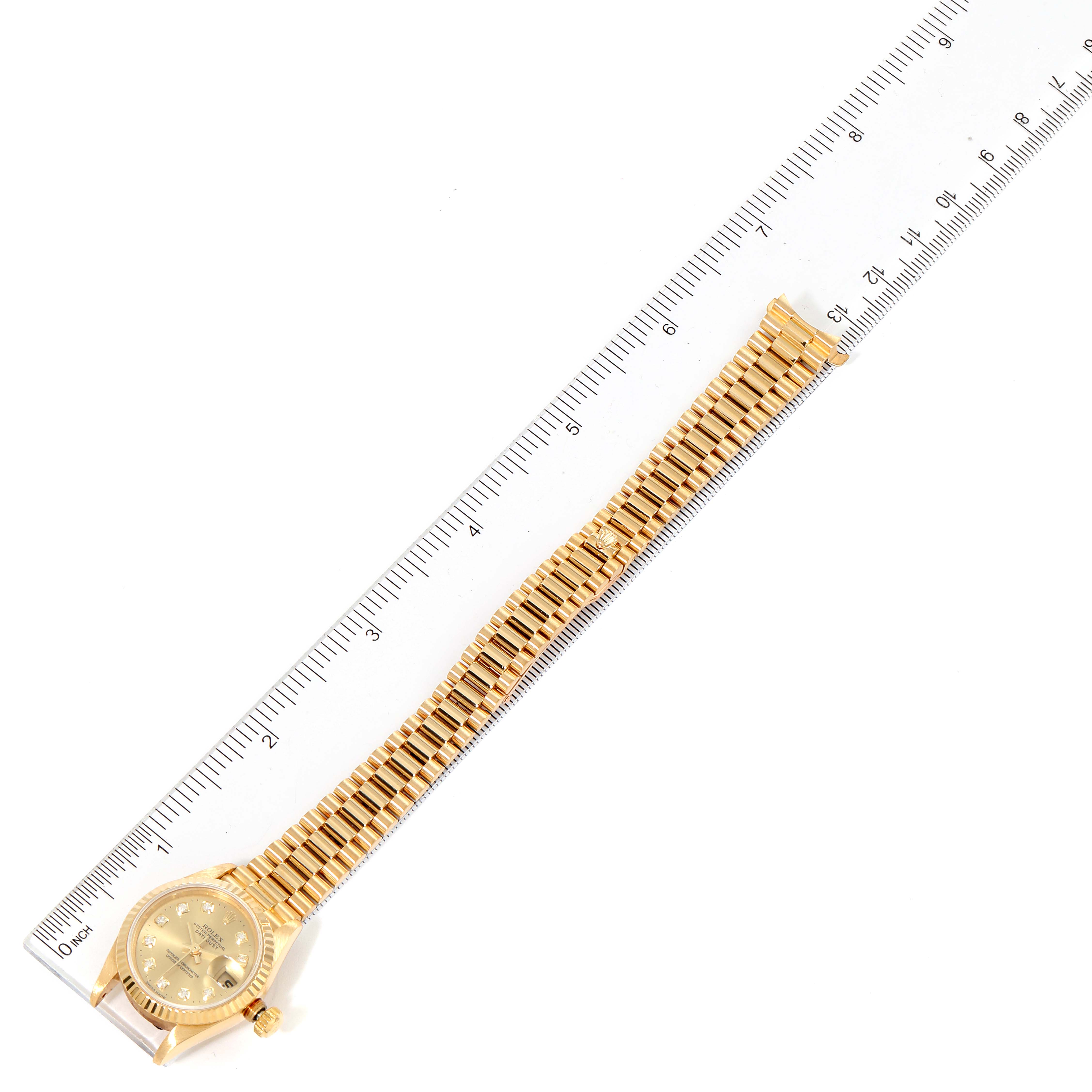 The image shows a Rolex President 69178 Women
s Yellow Gold Champagne Dial 69178 Women
s Yellow Gold Champagne Dial model watch laid flat next to a ruler, displaying the full bracelet and dial.