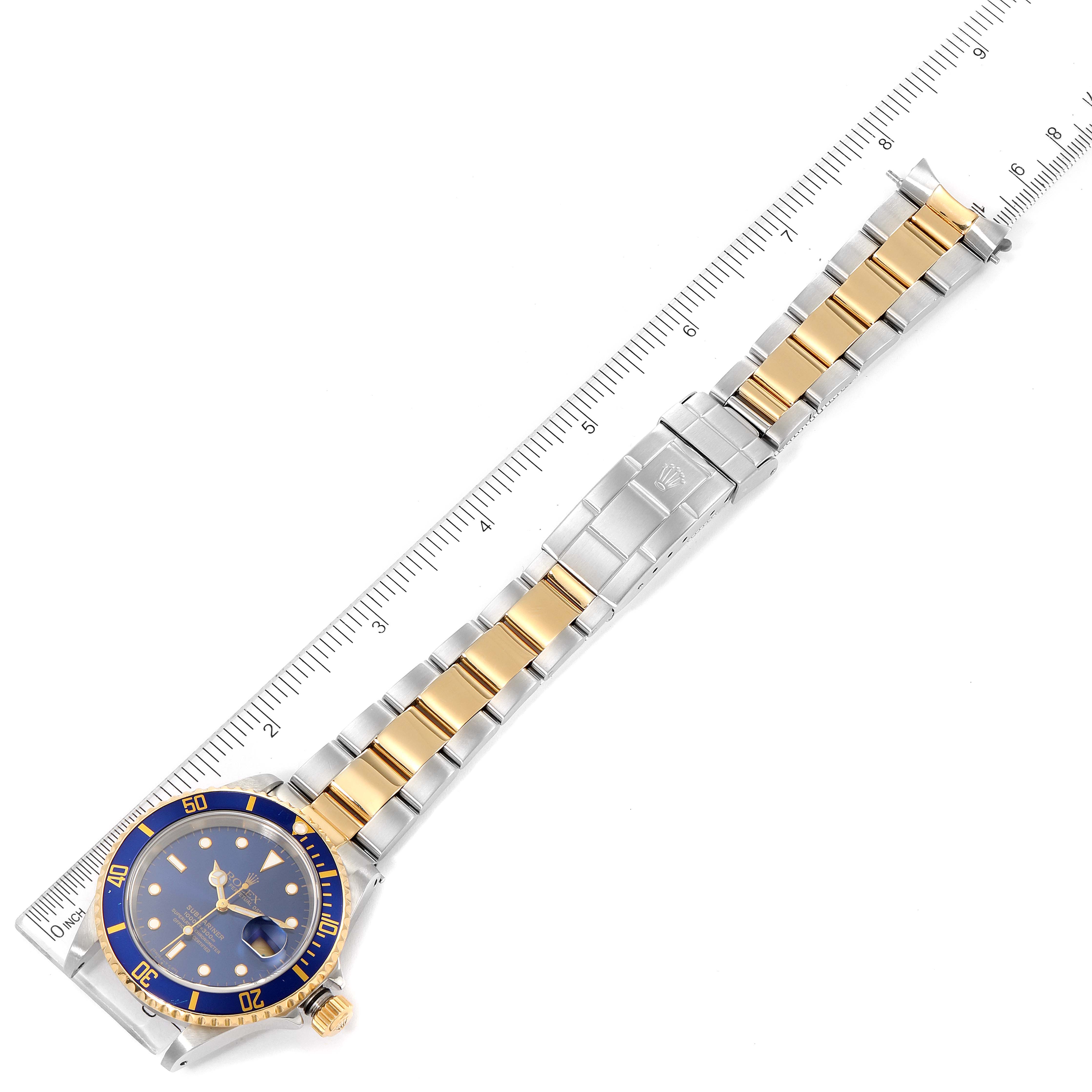 The image shows a Rolex Submariner 16613 Men's Steel and Gold (two tone) Blue Dial 16613 Men's Steel and Gold (two tone) Blue Dial watch with a two-tone bracelet, measured against a ruler, viewed from the top angle.