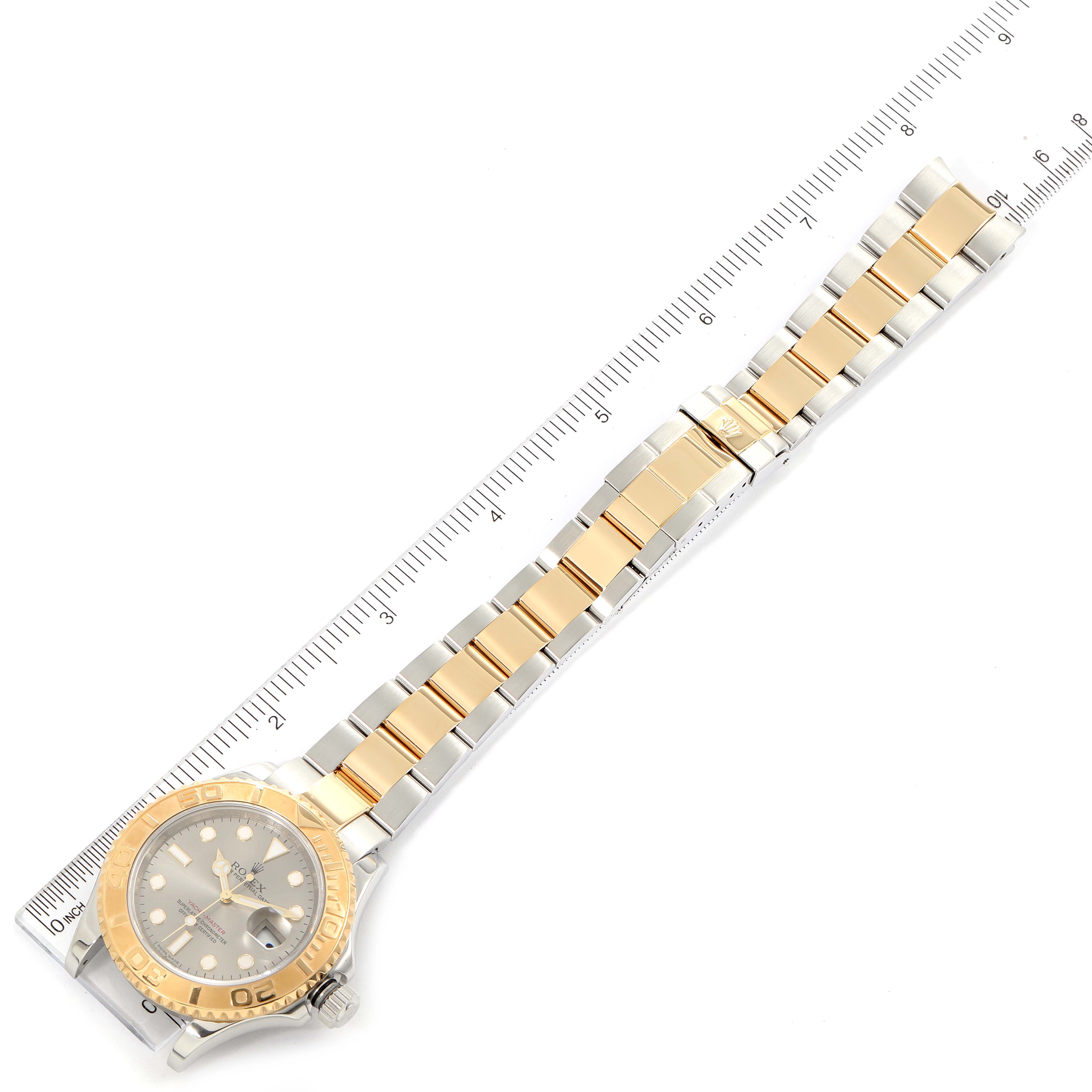 The image shows a Rolex Yacht-Master 16623 Men
s Steel and Gold (two tone) Grey Dial 16623 Men
s Steel and Gold (two tone) Grey Dial watch laid flat with its two-tone bracelet and bezel, next to a ruler for scale.