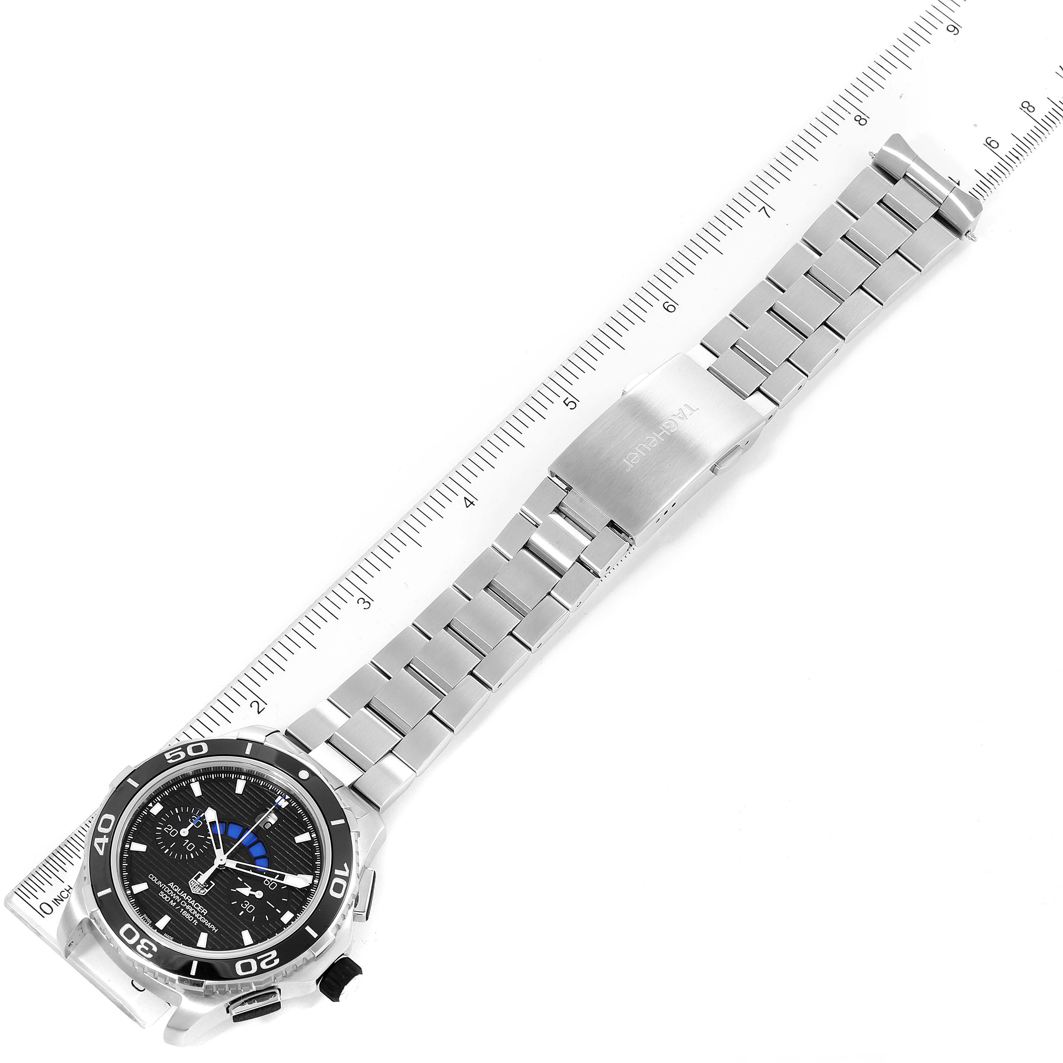 This image shows a Tag Heuer Aquaracer CAK211A Men's Stainless Steel Black Dial CAK211A Men's Stainless Steel Black Dial watch from an overhead angle, displaying the face, bezel, band, and clasp alongside a measuring ruler.