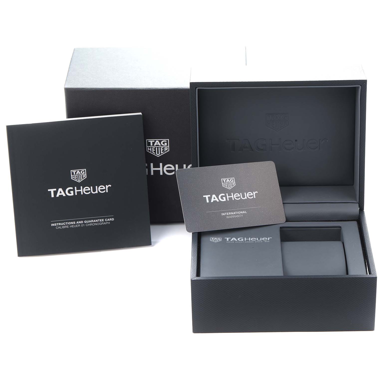 The image shows the packaging and accessories for a Tag Heuer Carrera model CAR205B watch, including the box, warranty card, and instruction manual.