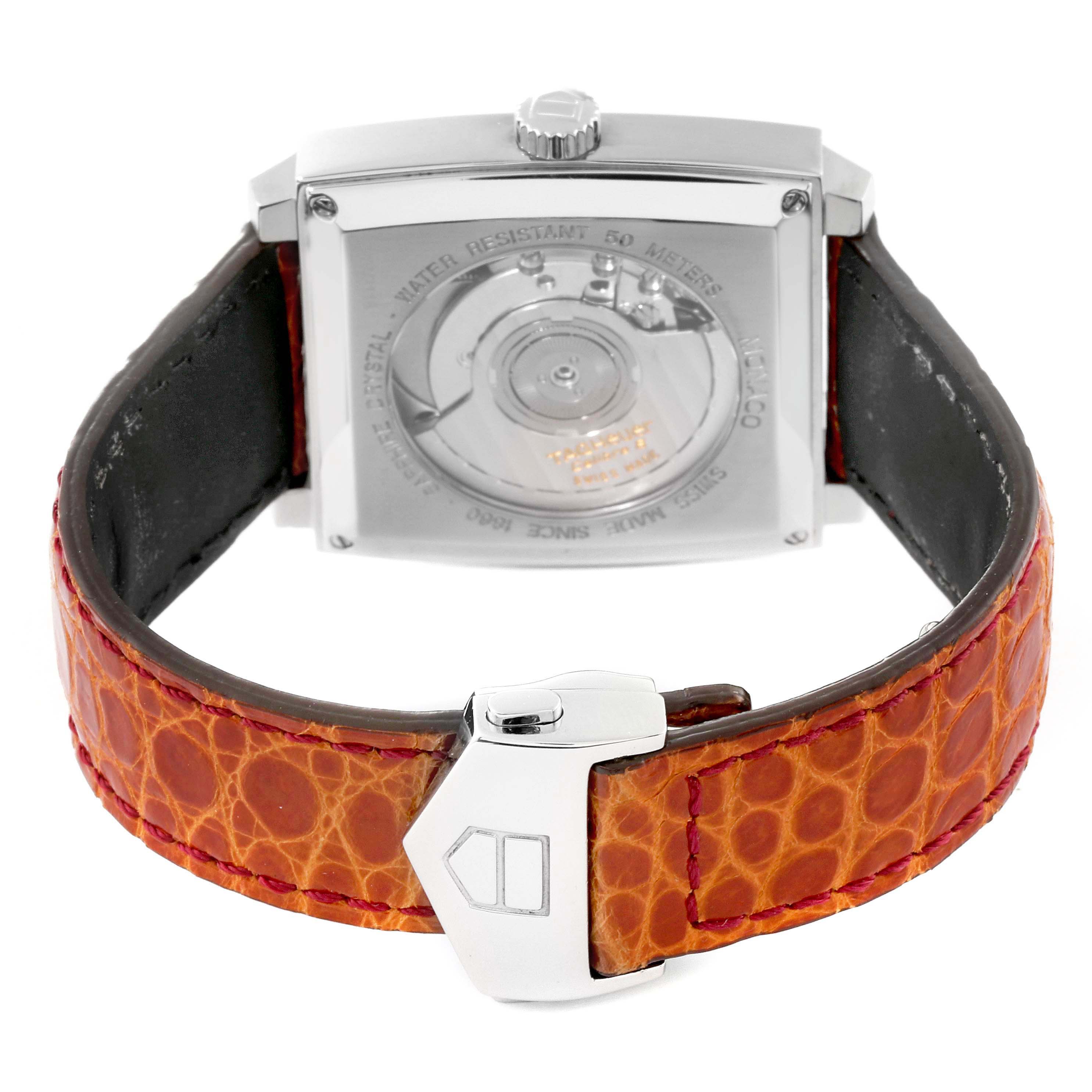 This image shows the back of the Tag Heuer Monaco 63480 Men's Stainless Steel Black Dial 63480 Men's Stainless Steel Black Dial watch and its orange leather strap with a clasp.