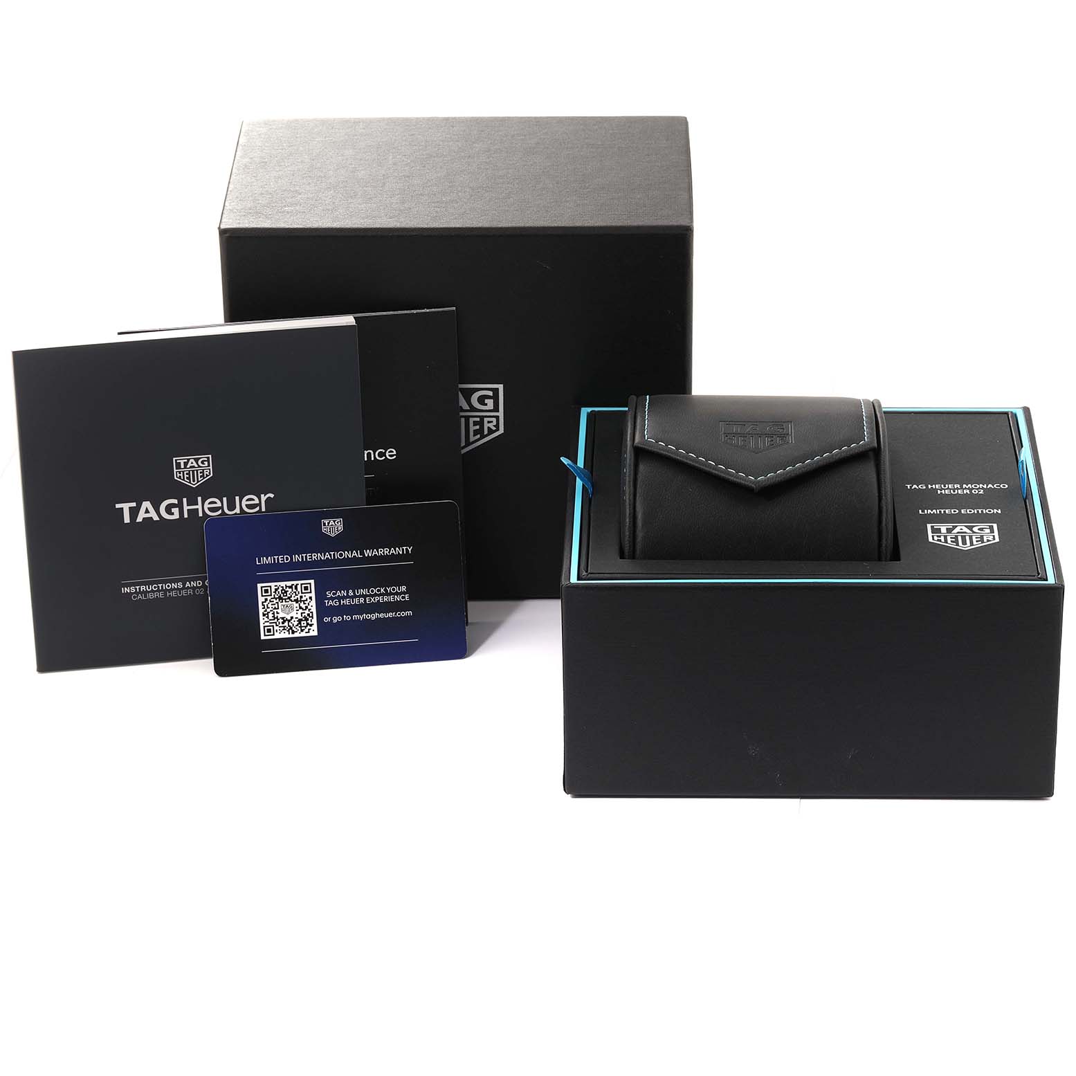 The image shows the packaging and accessories of a Tag Heuer Monaco CBL2181 Men's Titanium Grey Dial CBL2181 Men's Titanium Grey Dial watch, including a box, a travel case, manuals, and a warranty card.