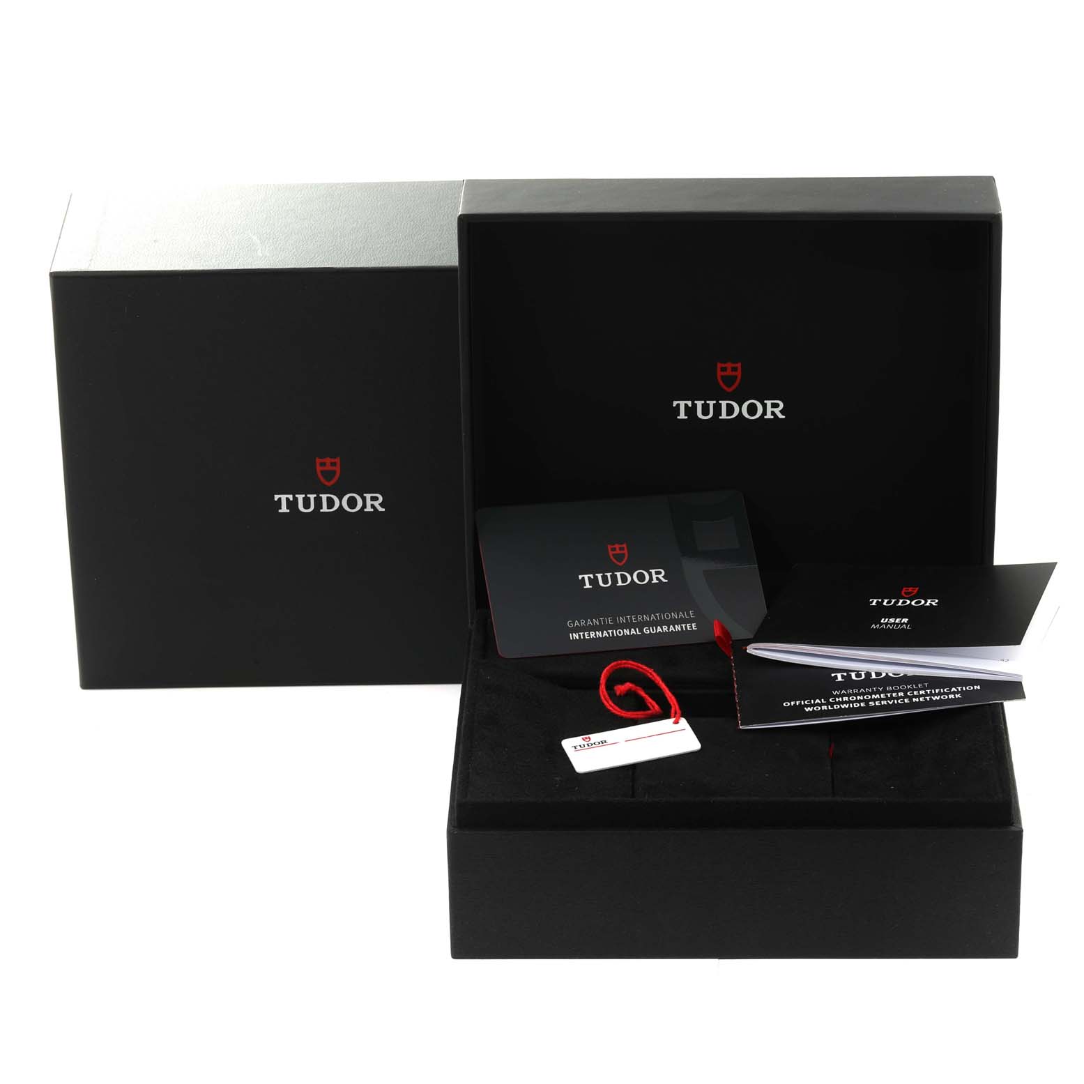 The image shows a Tudor Heritage Black Bay 79470 Men
s Stainless Steel Black Dial 79470 Men
s Stainless Steel Black Dial watch box at an angle, along with the international guarantee card, booklet, and tags.