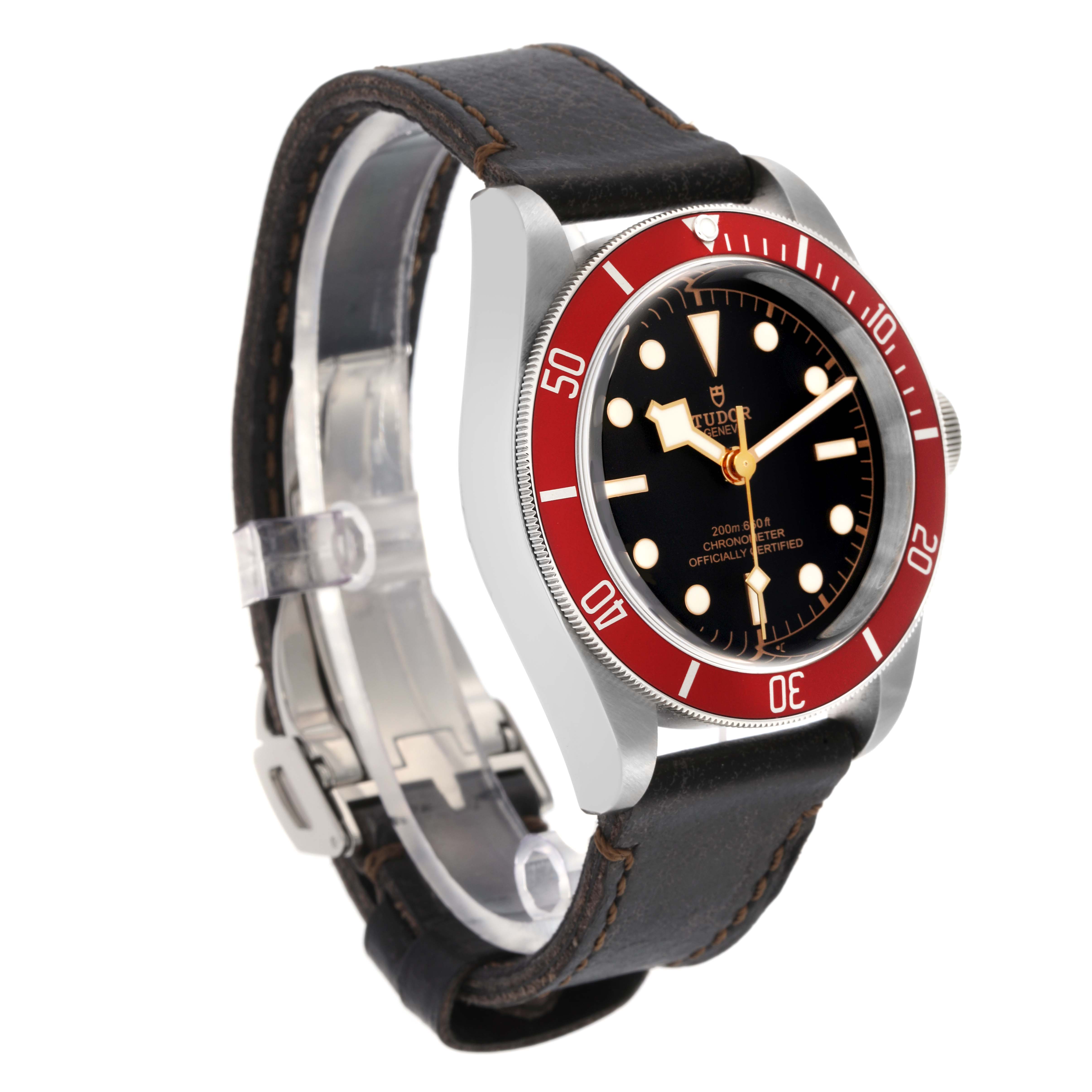 The Tudor Heritage Black Bay model 79230R is shown at an angled side view, displaying the watch face, red bezel, crown, and leather strap.