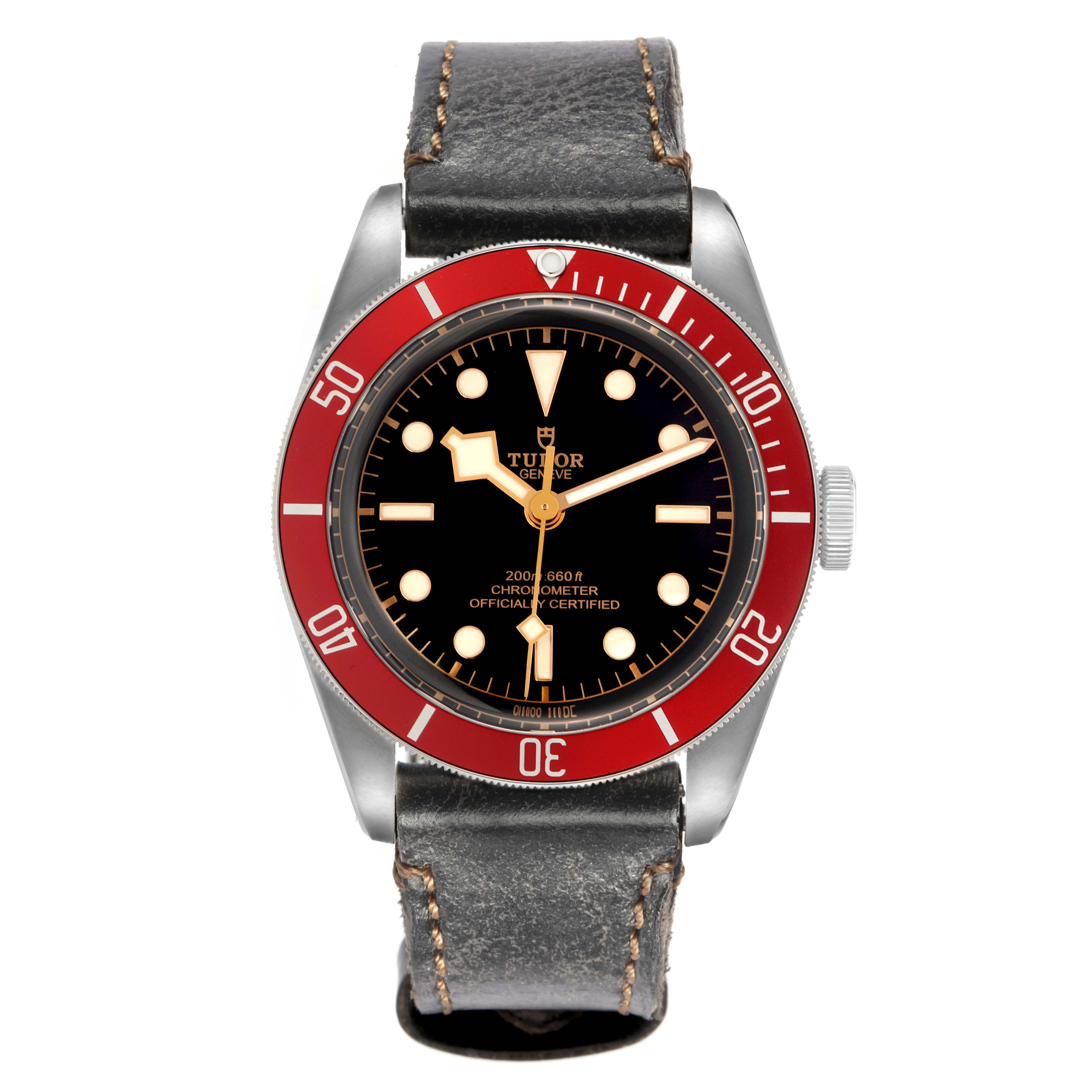 The Tudor Heritage Black Bay model 79230R is shown from a front angle, displaying its red bezel, black dial, and leather strap.