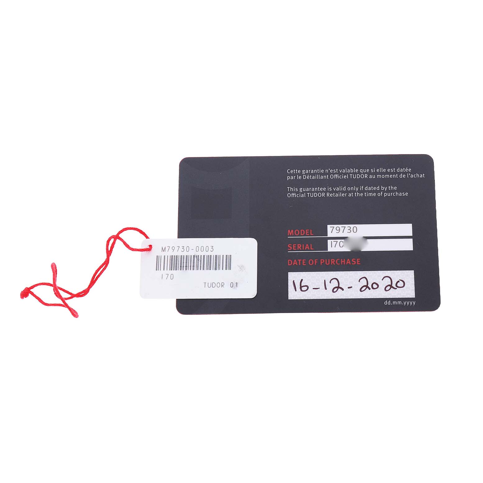 The image shows a Tudor Heritage Black Bay M79730-003 Men's Stainless Steel Black Dial warranty card with model and serial numbers, alongside a red stringed tag.