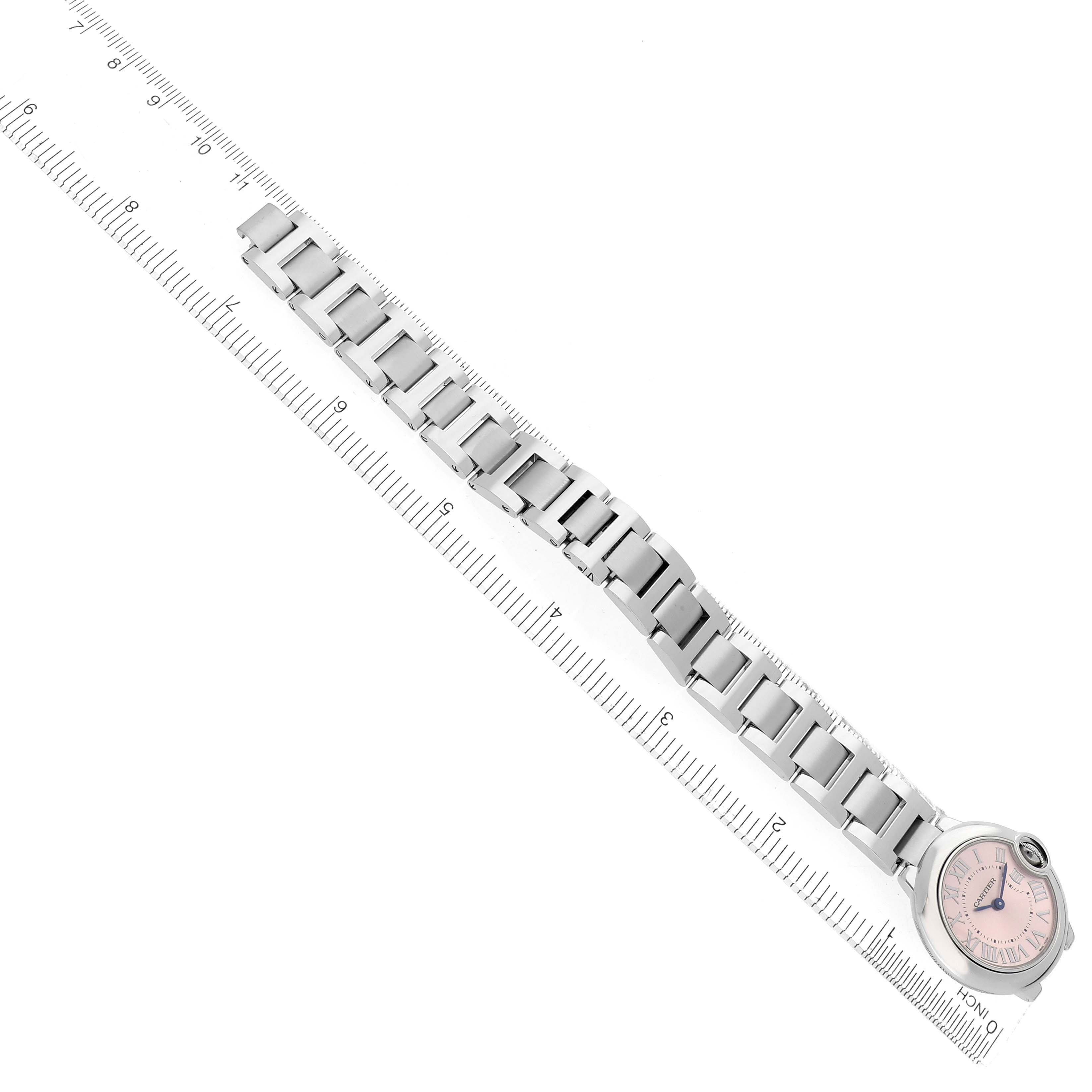 The image shows a Cartier Ballon Bleu W6920038 men's watch laid flat, emphasizing its metal bracelet and round face, against a ruler for scale.