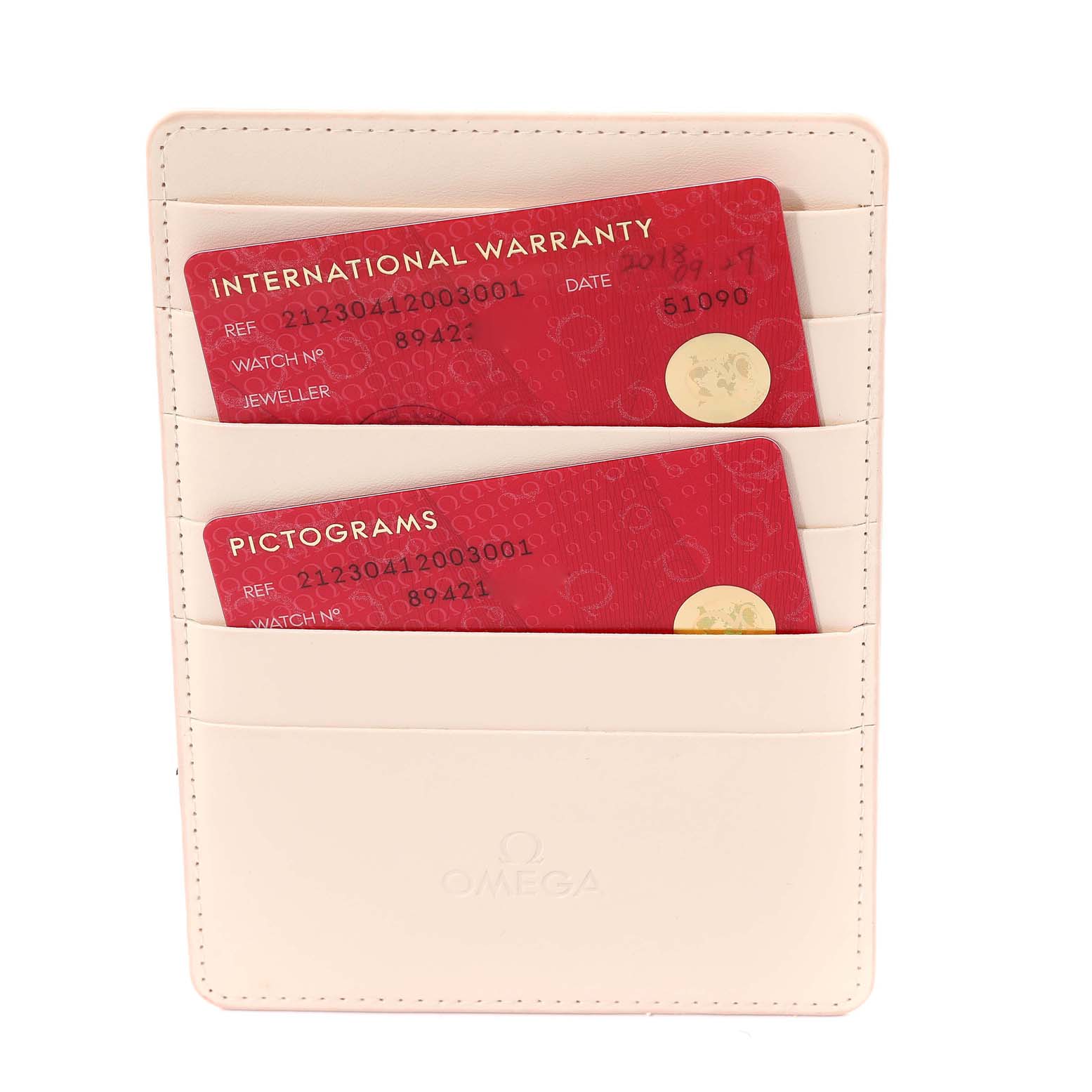 This image shows a white Omega cardholder holding red "International Warranty" and "Pictograms" cards for a Seamaster model.