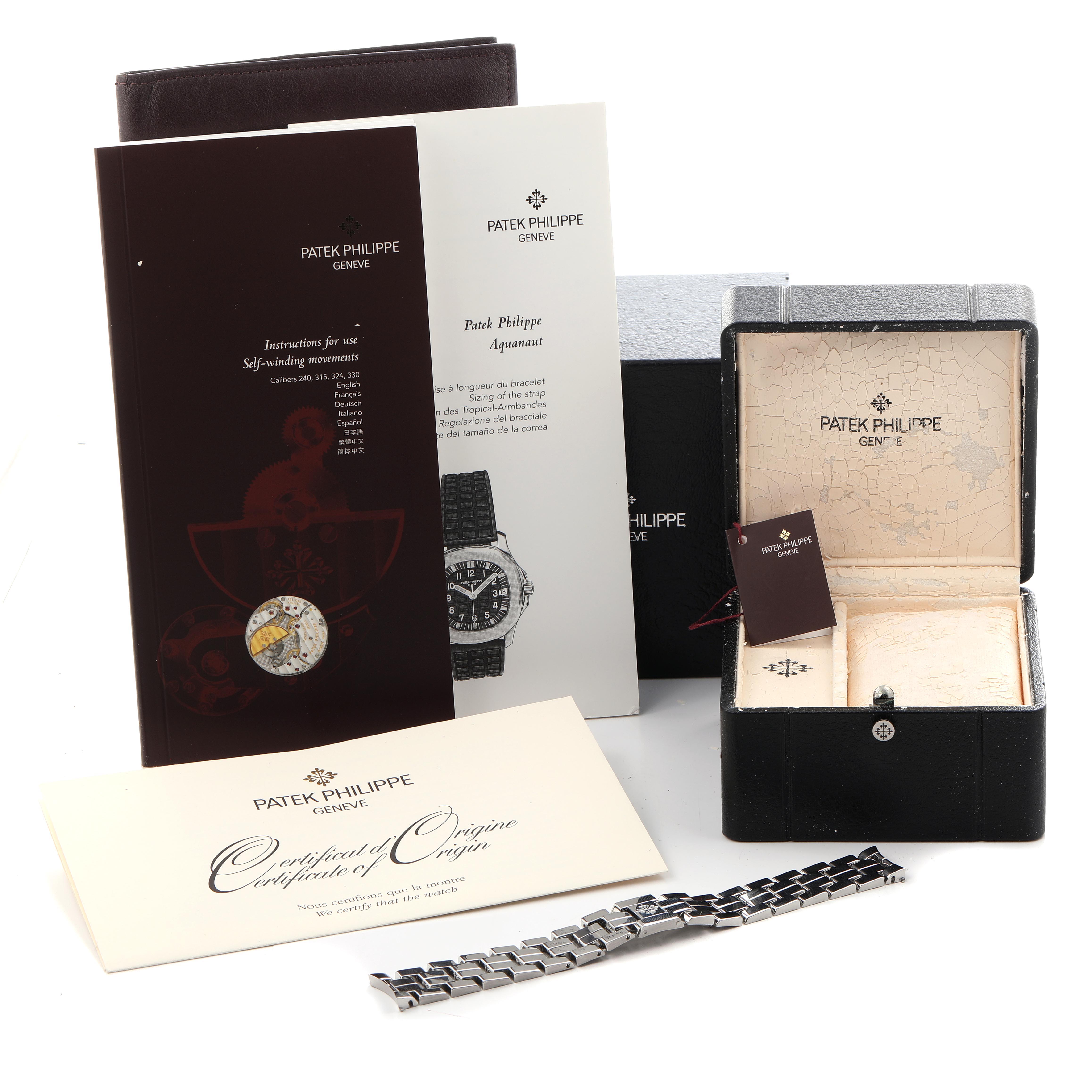 The image shows Patek Philippe Aquanaut model 5065/1A-001 accessories, including its box, brochures, certificate of origin, and a metal bracelet.