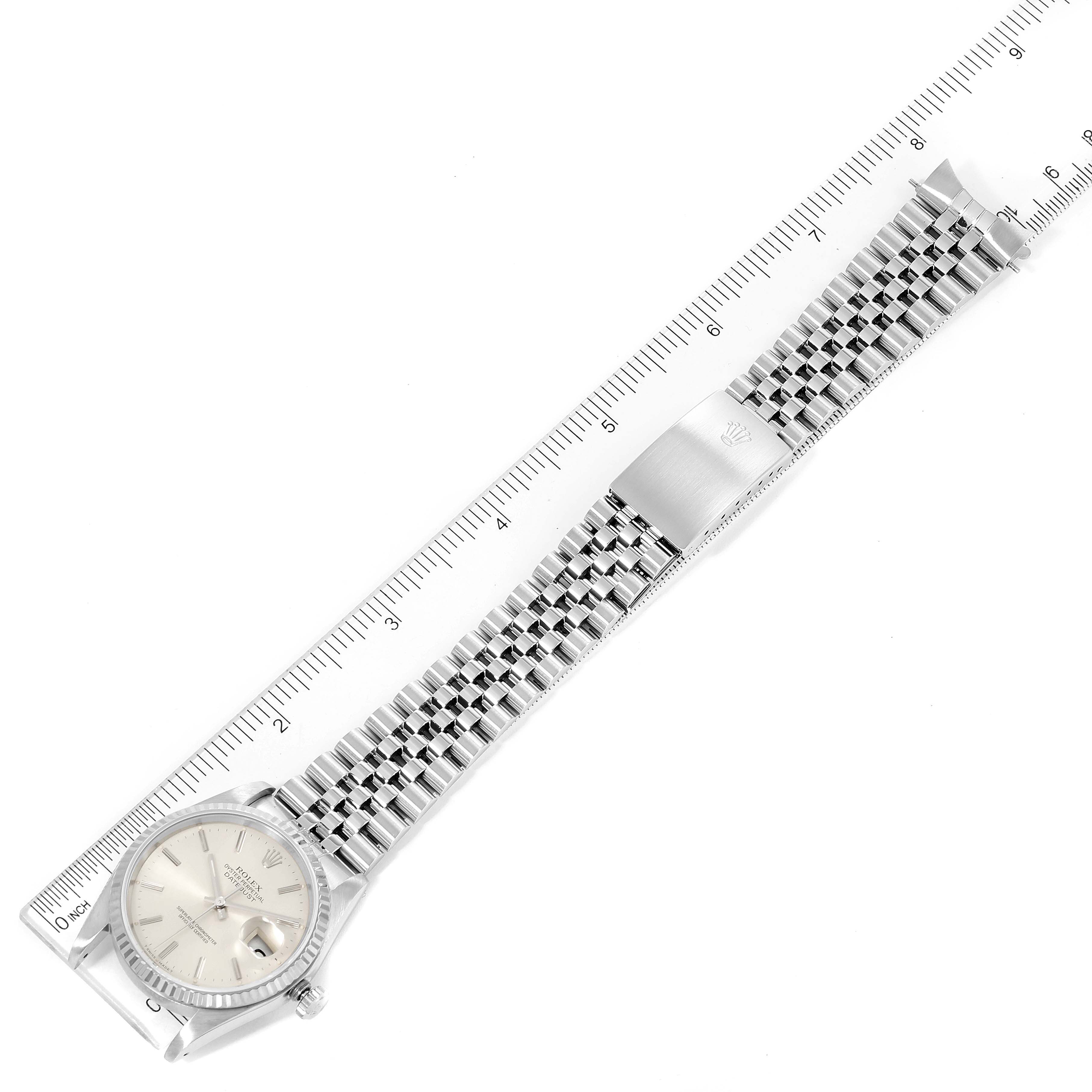 The Rolex Datejust 16234 Men's Stainless Steel Silver Dial 16234 Men's Stainless Steel Silver Dial watch is shown flat with a ruler alongside it, displaying the entire watch, including the face and bracelet.