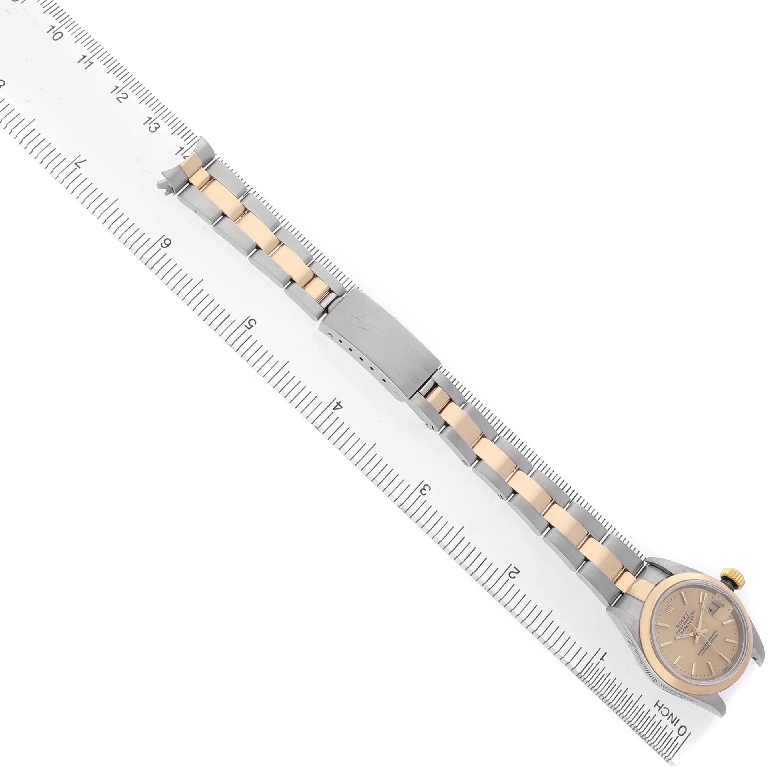 The Rolex Datejust 79163 Men's Steel and Gold (two tone) Champagne Dial watch is shown from a top-down angle, displaying the bracelet, clasp, and partially the case on a ruler.