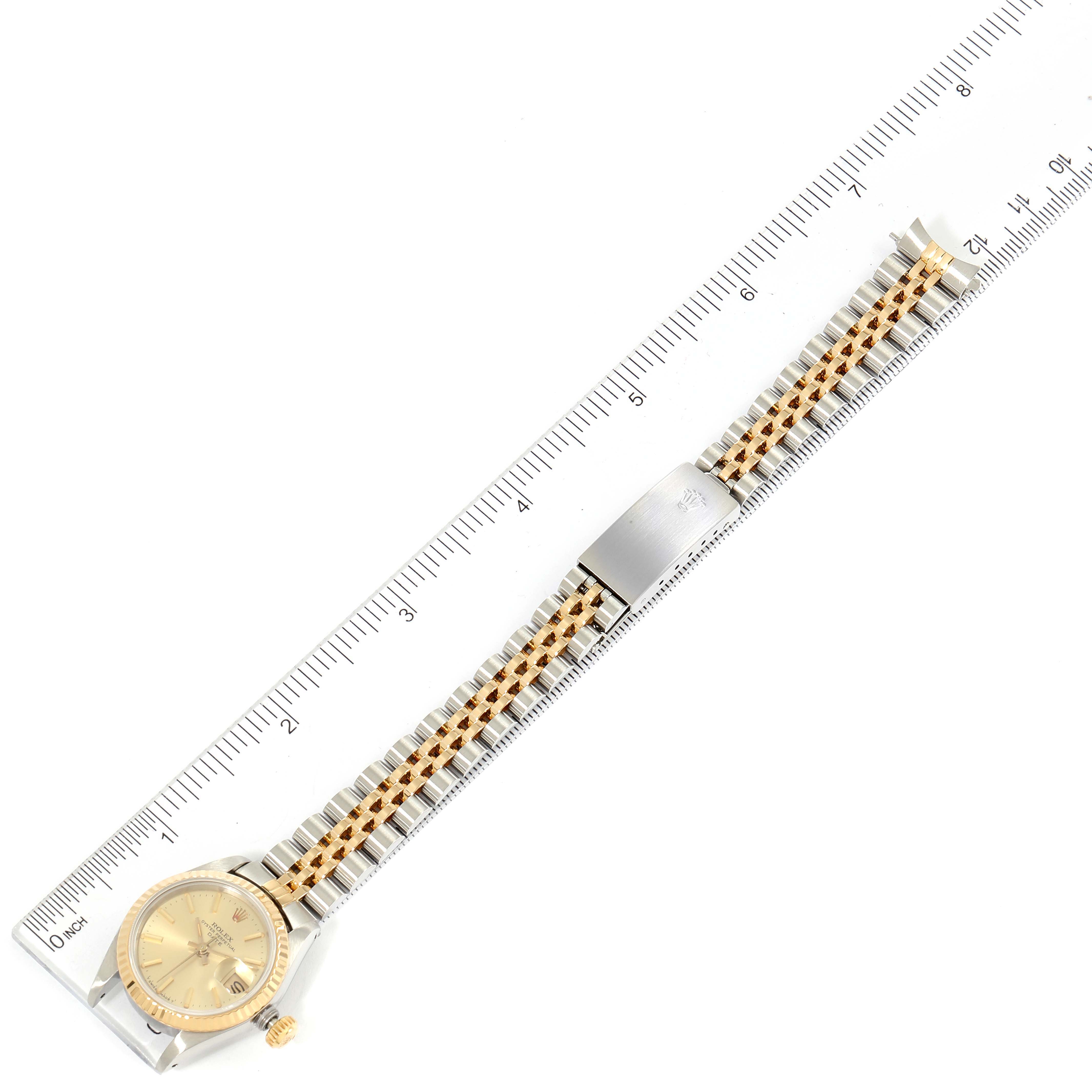 The Rolex Datejust 69173 Women's Steel and Gold (two tone) Champagne Dial 69173 Women's Steel and Gold (two tone) Champagne Dial watch is shown from a top-down angle, displaying the face and full metal band against a ruler for scale.