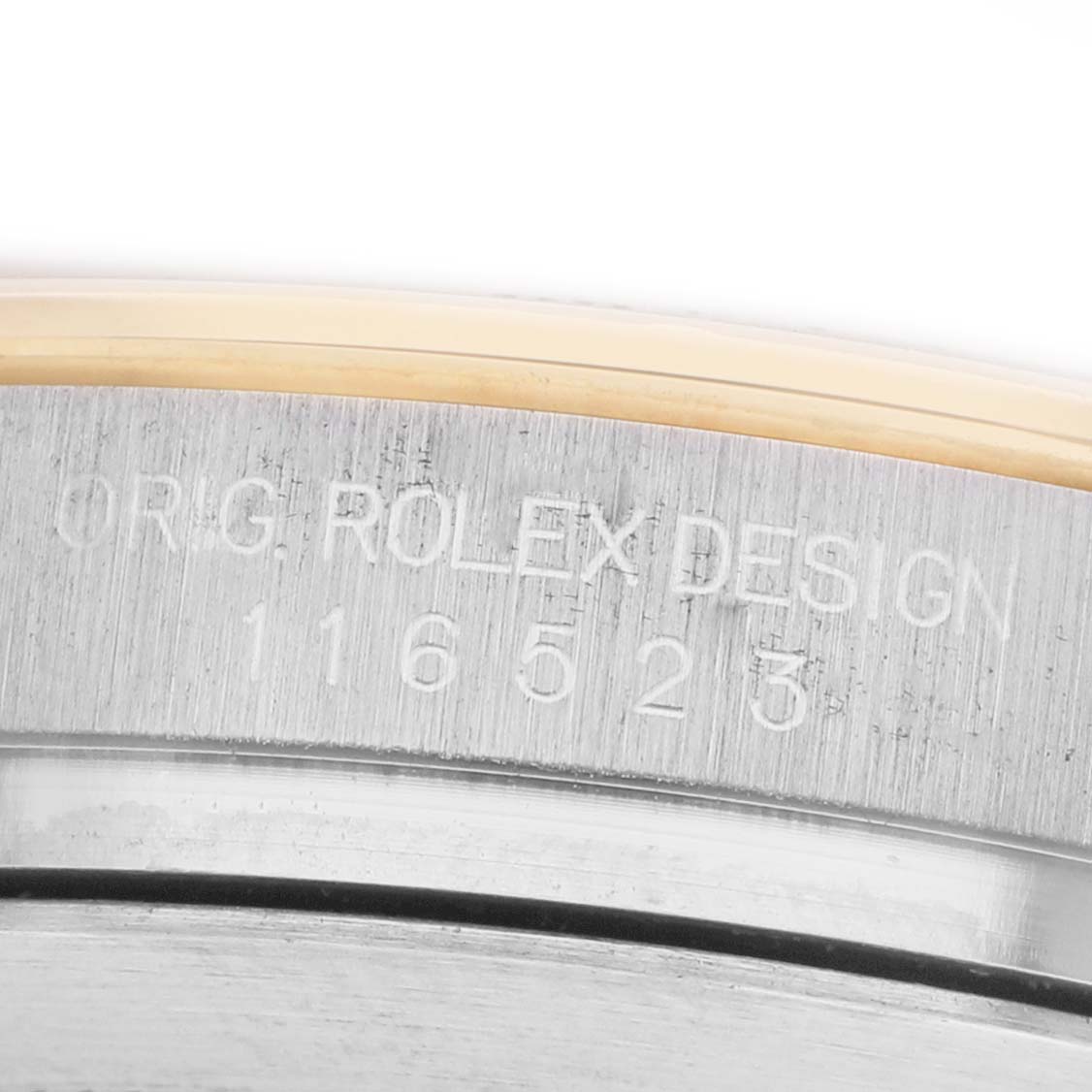 The image shows a close-up of the side of a Rolex Daytona 116523 Men's Steel and Gold (two tone) Black Dial watch, highlighting the engraved model and design number.