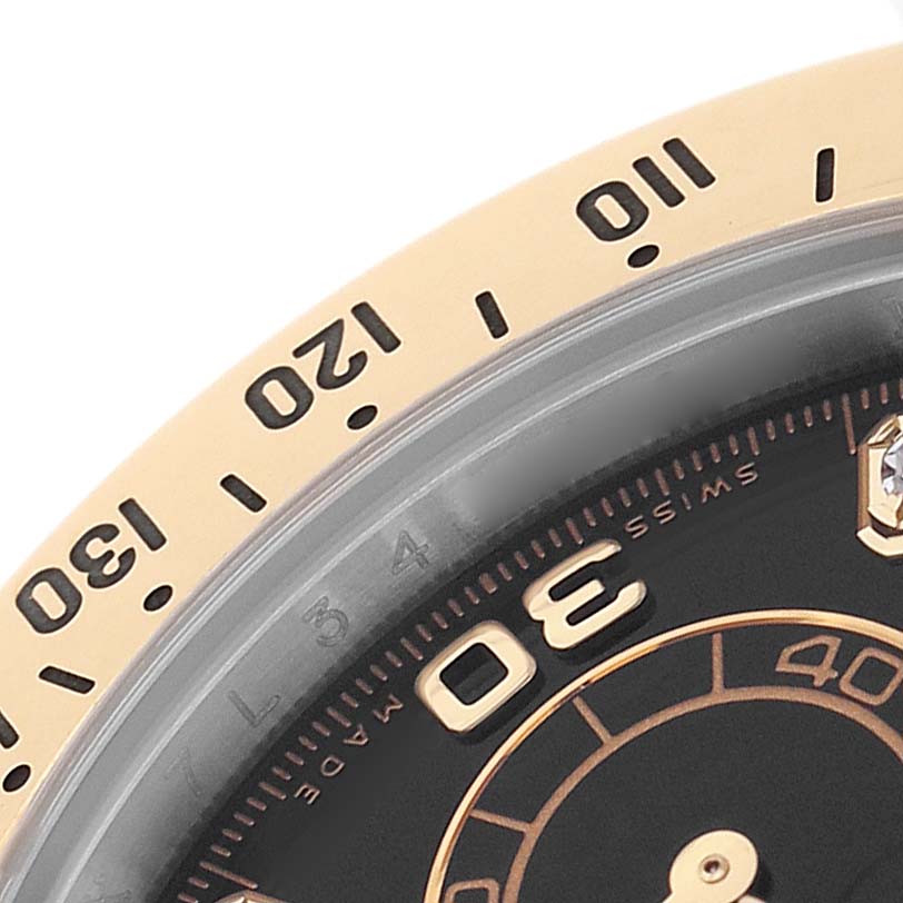 The image shows a close-up of the Rolex Daytona 116523 Men's Steel and Gold (two tone) Black Dial watch's bezel, highlighting its markings and edge.