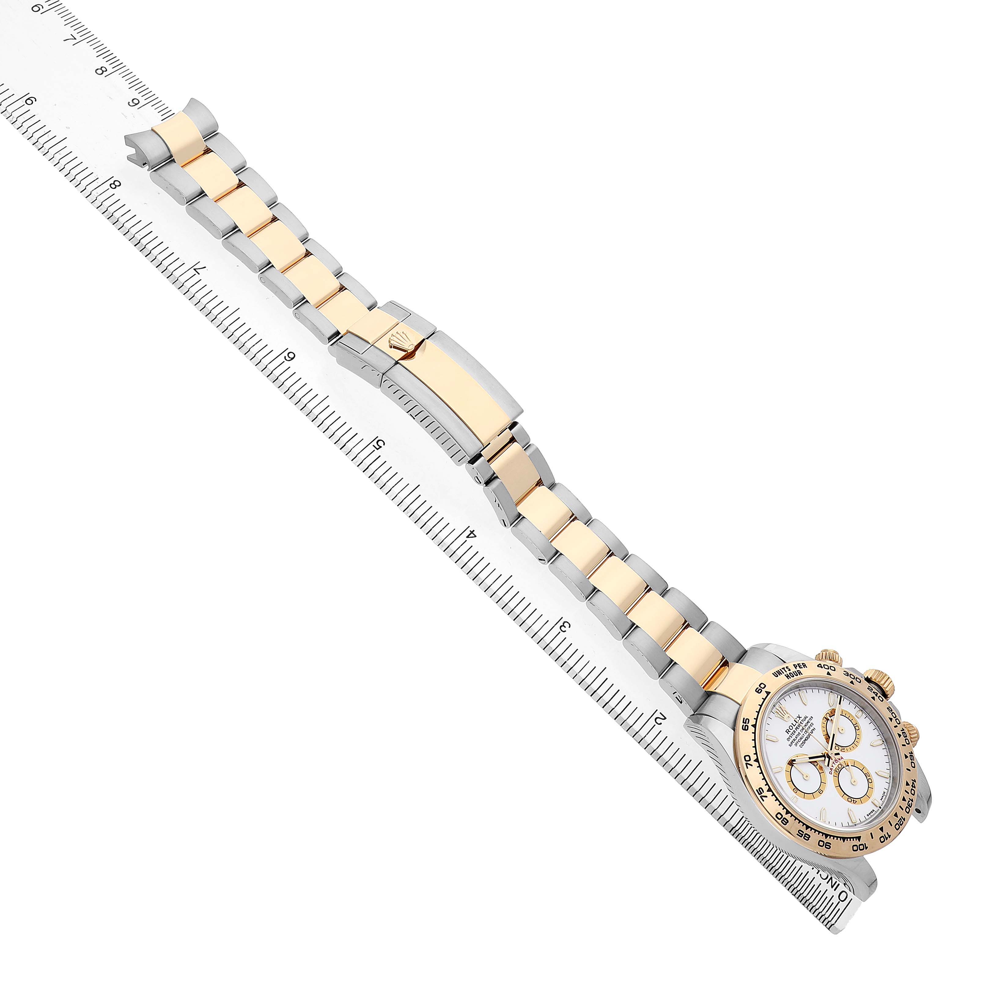 The Rolex Daytona M126503-0001 Men's Steel and Gold (two tone) White Dial watch is shown at a diagonal angle, highlighting the bracelet and clasp alongside a ruler.
