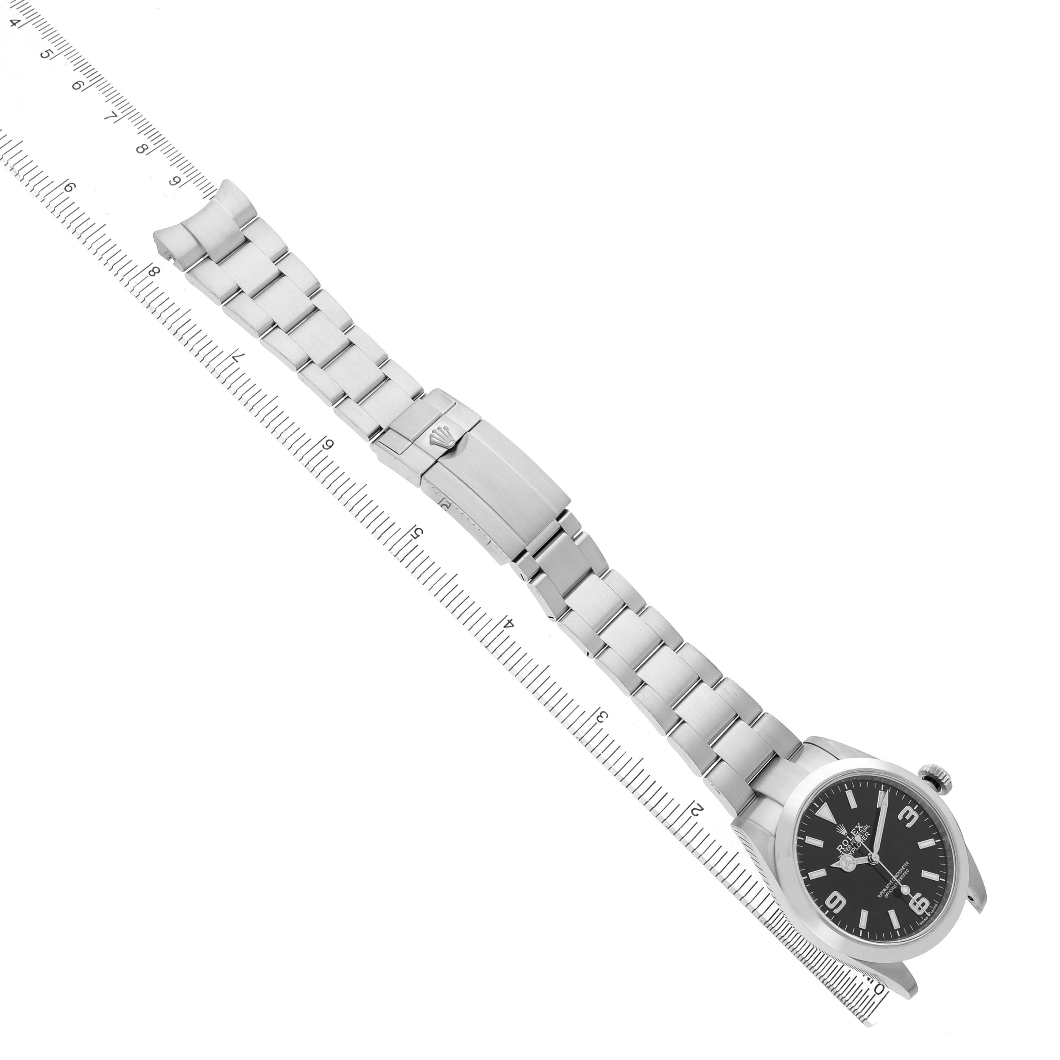 The image shows a Rolex Explorer 224270 Men's Stainless Steel Black Dial watch at an angle, highlighting its face, bracelet, and clasp next to a ruler for scale.