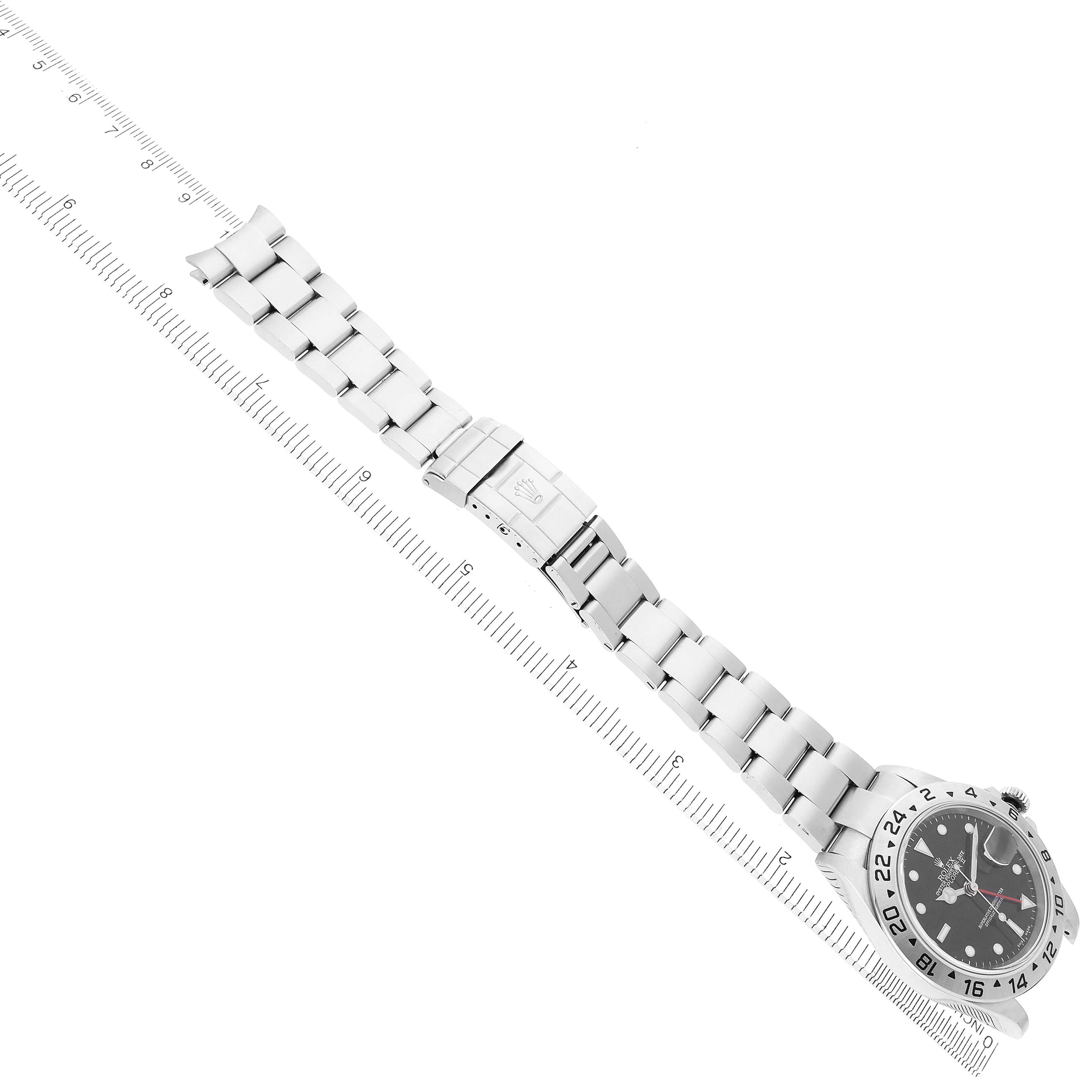 The image shows a Rolex Explorer model 216570 men's watch at a diagonal angle, displaying the full watch, bracelet, clasp, and face alongside a ruler for scale.