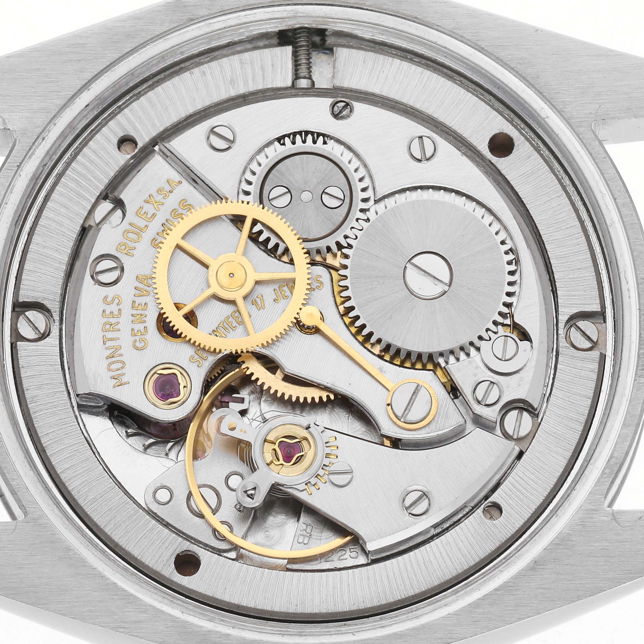 This image shows the movement of a Rolex Date watch, model number 6694, featuring gears, jewels, and intricate mechanical components.