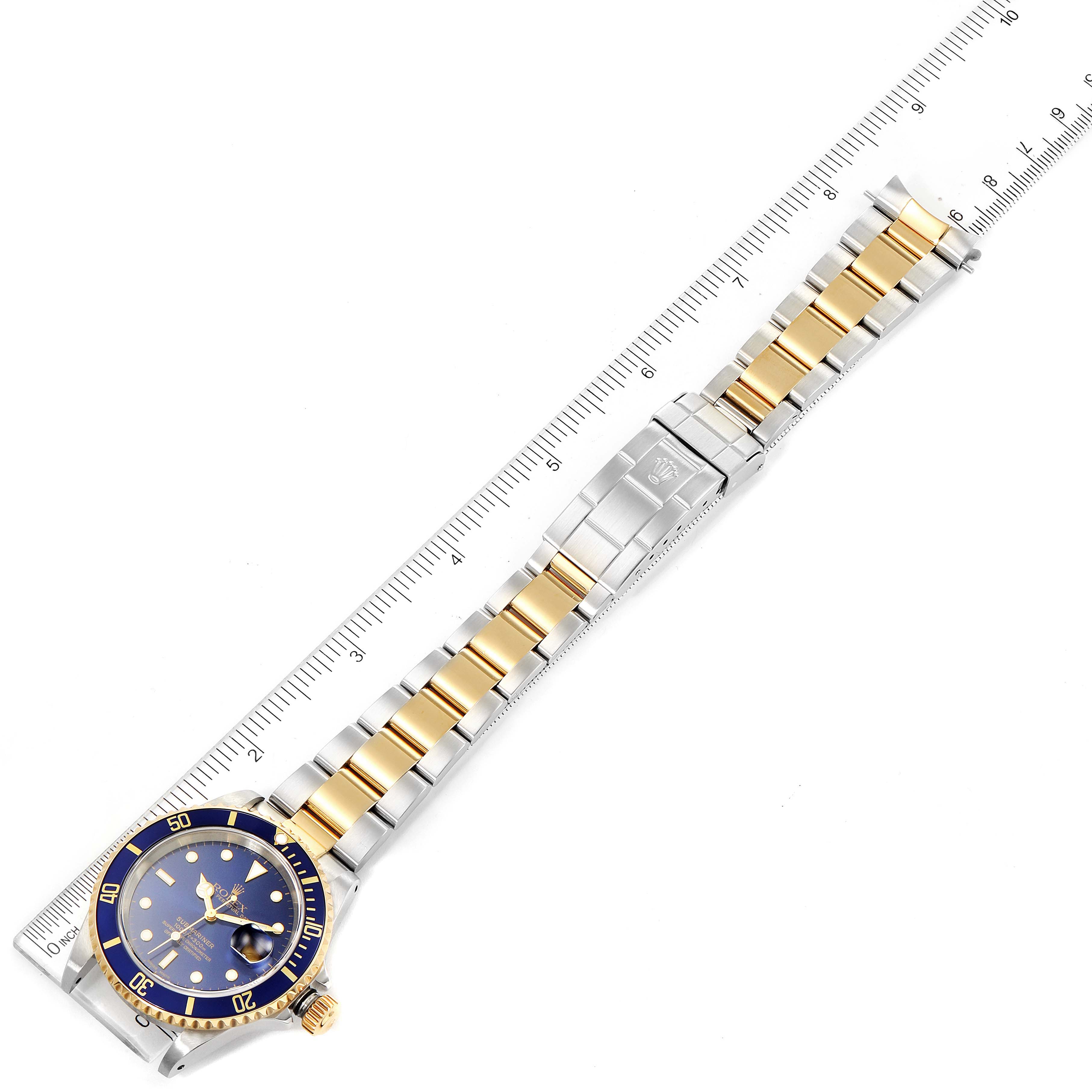 The image shows a top-down view of a Rolex Submariner 16613 Men's Steel and Gold (two tone) Blue Dial 16613 Men's Steel and Gold (two tone) Blue Dial model watch, fully extended with a ruler for scale.