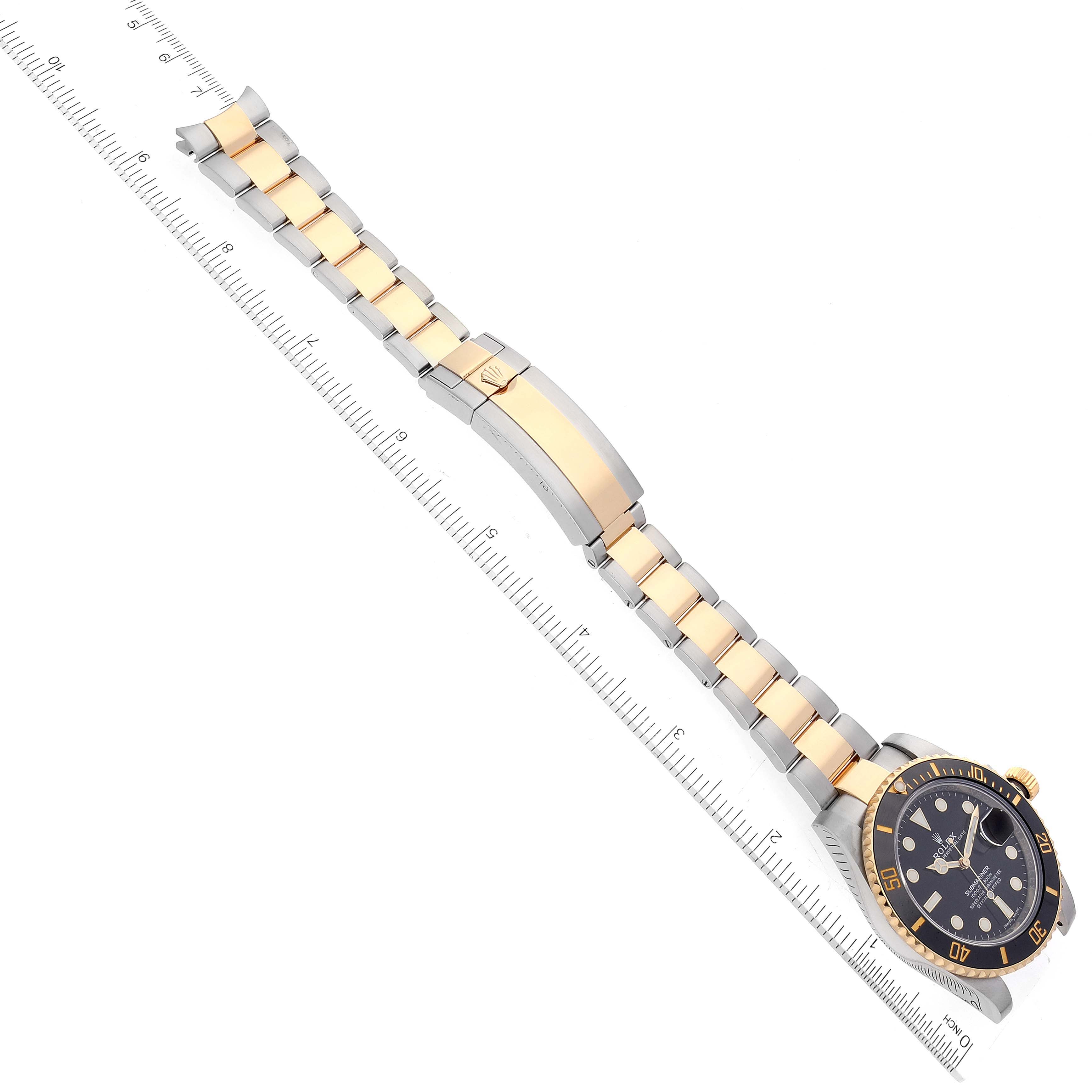The image displays a Rolex Submariner 116613 Men
s Steel and Gold (two tone) Black Dial 116613 Men
s Steel and Gold (two tone) Black Dial watch with a two-tone bracelet laid flat beside a ruler for scale.
