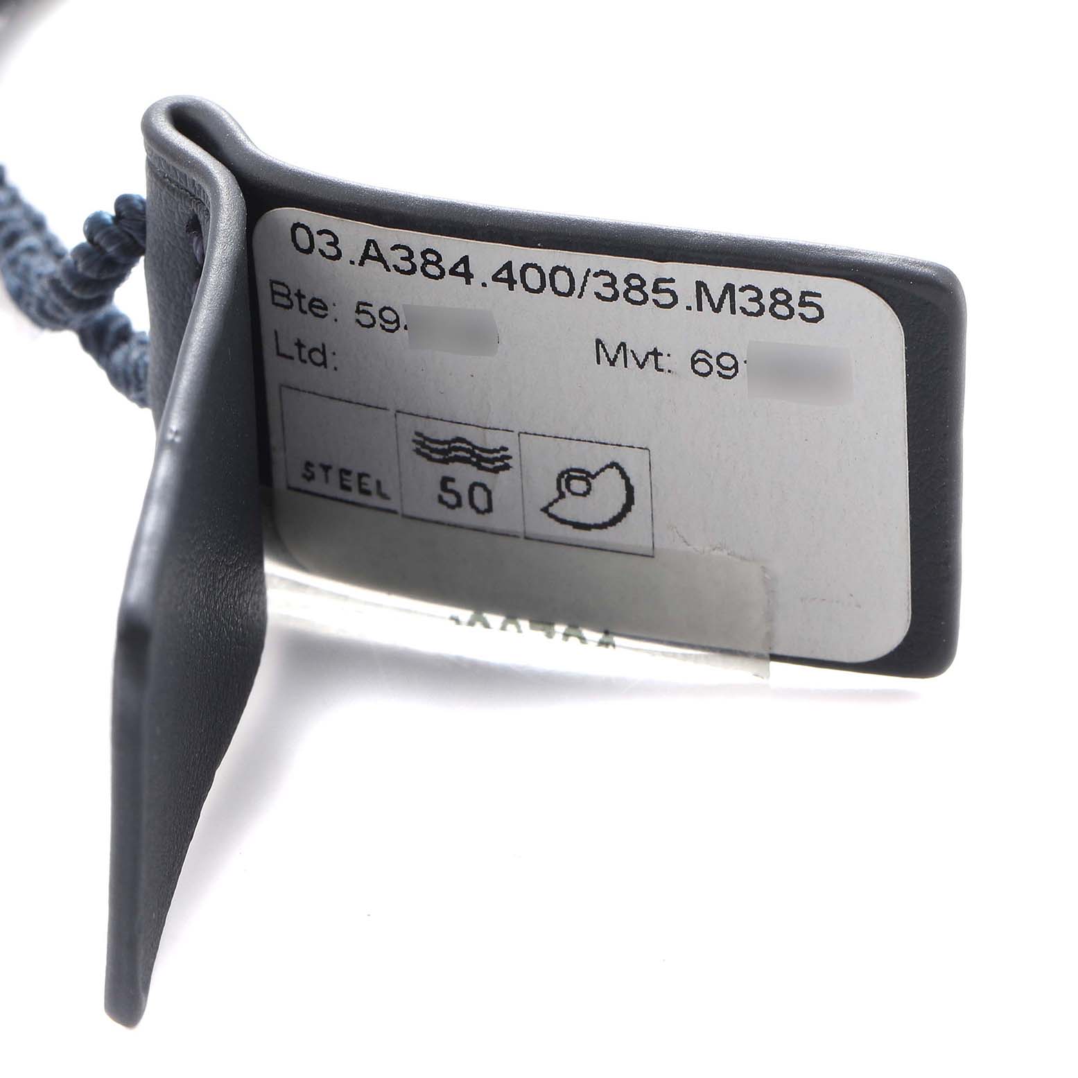 The image shows a tag for a Zenith Chronomaster, model number 03.A384.400/385.M385, displaying technical information and specifications from a side angle.