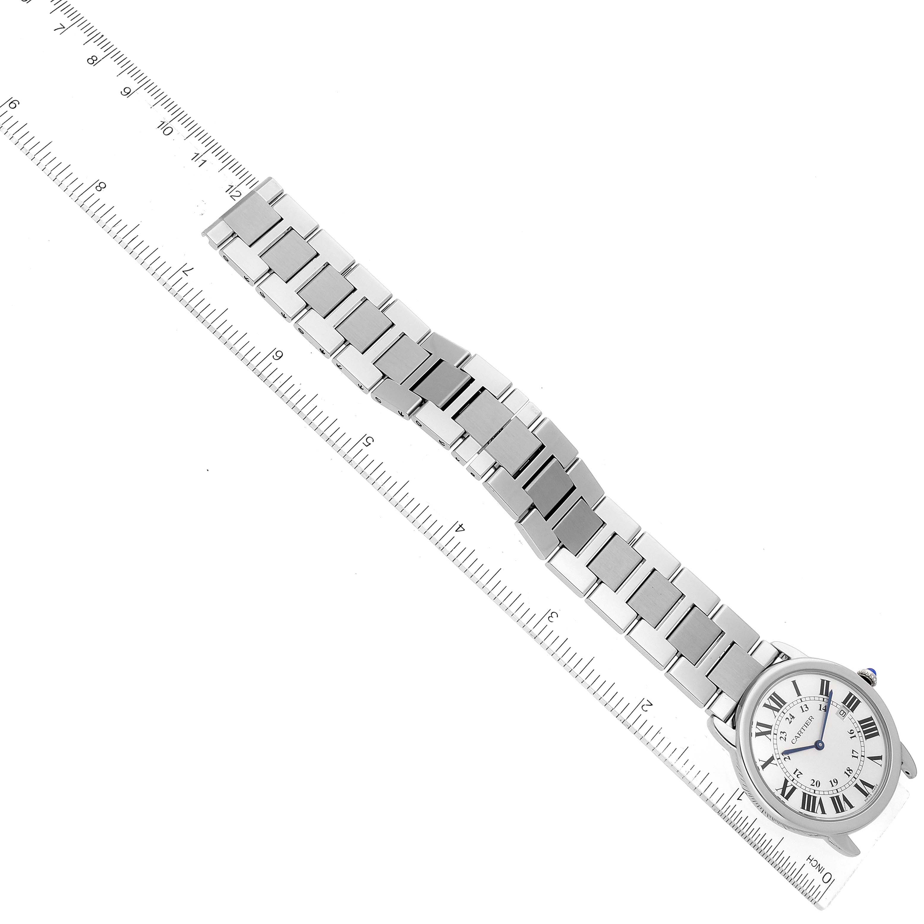 The image shows a top-down view of a Cartier Ronde W6701005 Men
s Stainless Steel Silver Dial W6701005 Men
s Stainless Steel Silver Dial watch, including its face and metal bracelet, alongside a ruler for scale.