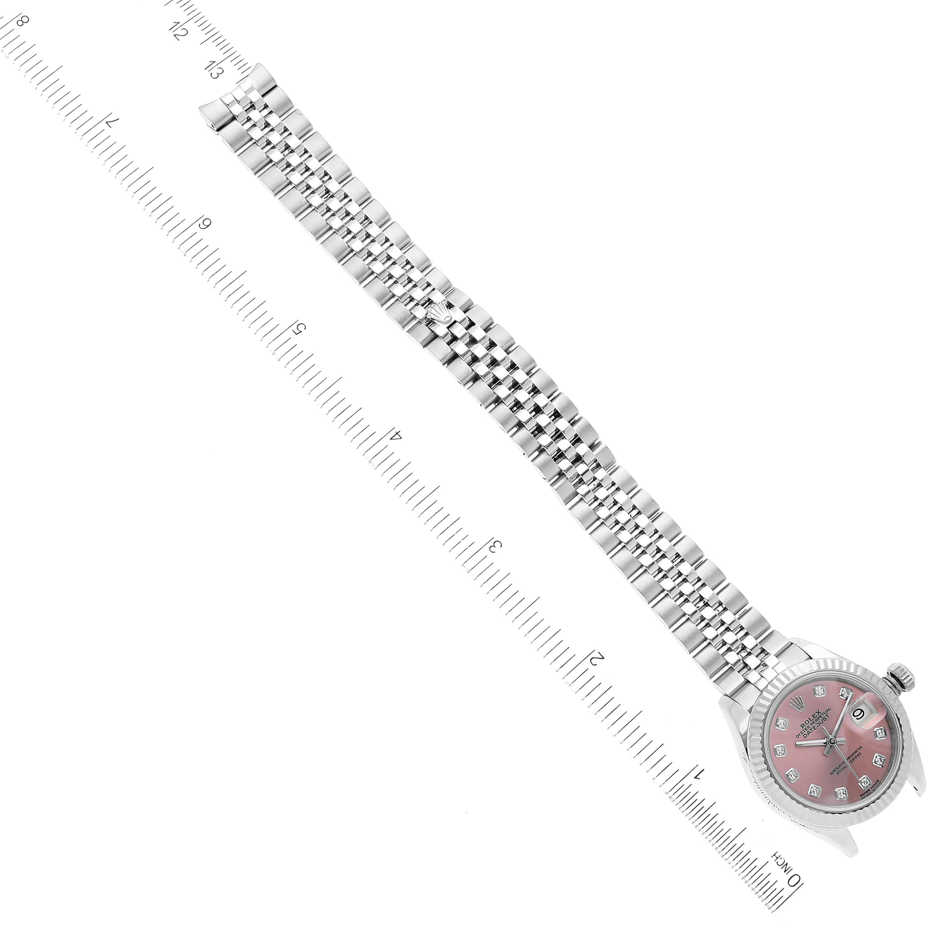 The image shows a Rolex Datejust 279174 Women's Stainless Steel Pink Dial 279174 Women's Stainless Steel Pink Dial watch from a top-down angle, highlighting its pink dial, fluted bezel, and Jubilee bracelet with a ruler for scale.