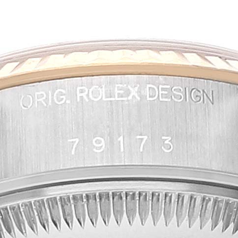 This close-up shot shows the side of a Rolex Datejust 79173 Women
s Steel and Gold (two tone) Champagne Dial 79173 Women
s Steel and Gold (two tone) Champagne Dial watch case, revealing the bezel and "ORIG. ROLEX DESIGN" engravings with the model number 79173.