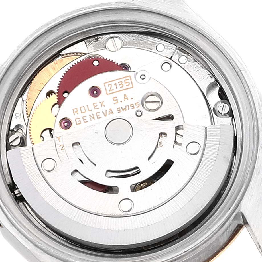 The image shows the internal movement mechanism of the Datejust Rolex watch, revealing gears and the rotor.