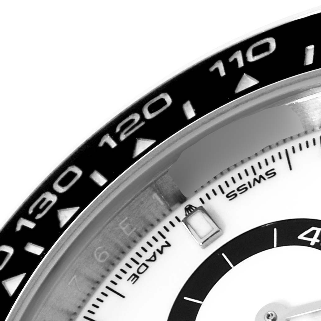 The image shows a close-up of the bezel and part of the dial of a Rolex Daytona 126500 Men's Stainless Steel White Dial 126500 Men's Stainless Steel White Dial watch.