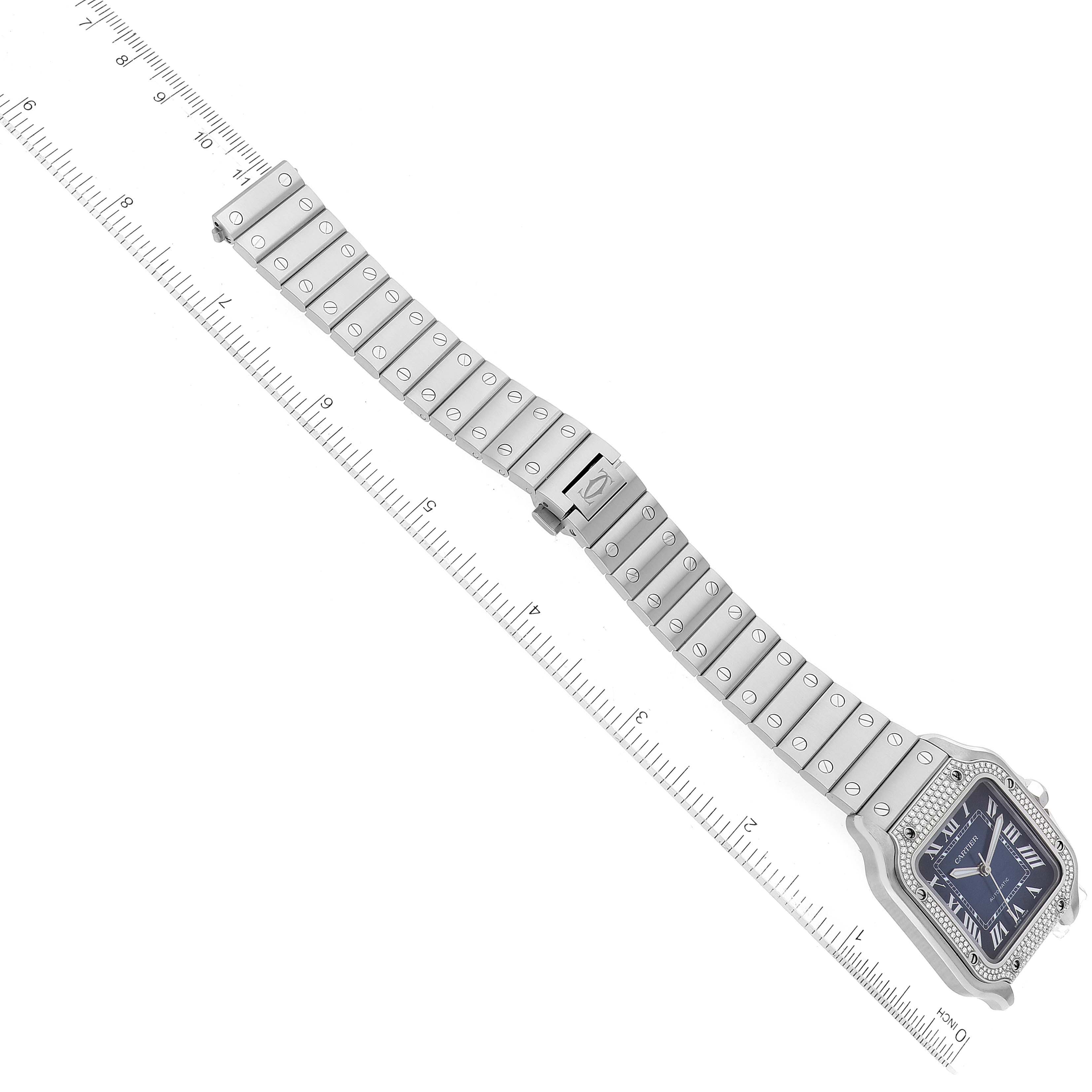 This image shows a Santos model watch by Cartier at an angled top view, highlighting its face and metal bracelet on a ruler.