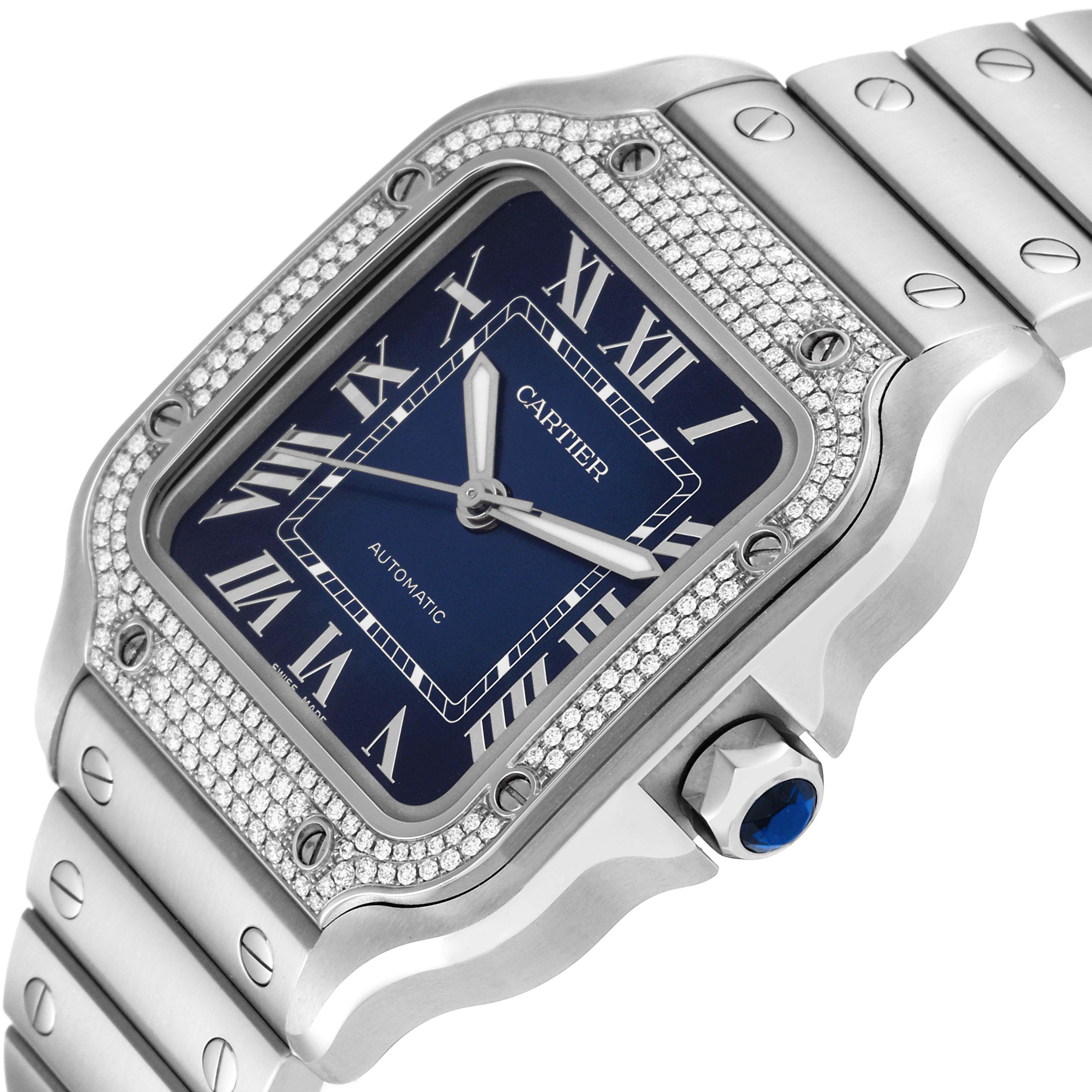 The image shows a Cartier Santos W4SA0006 Men's Stainless Steel Blue Dial W4SA0006 Men's Stainless Steel Blue Dial watch at an angle, highlighting its blue dial, Roman numerals, and diamond-set bezel.