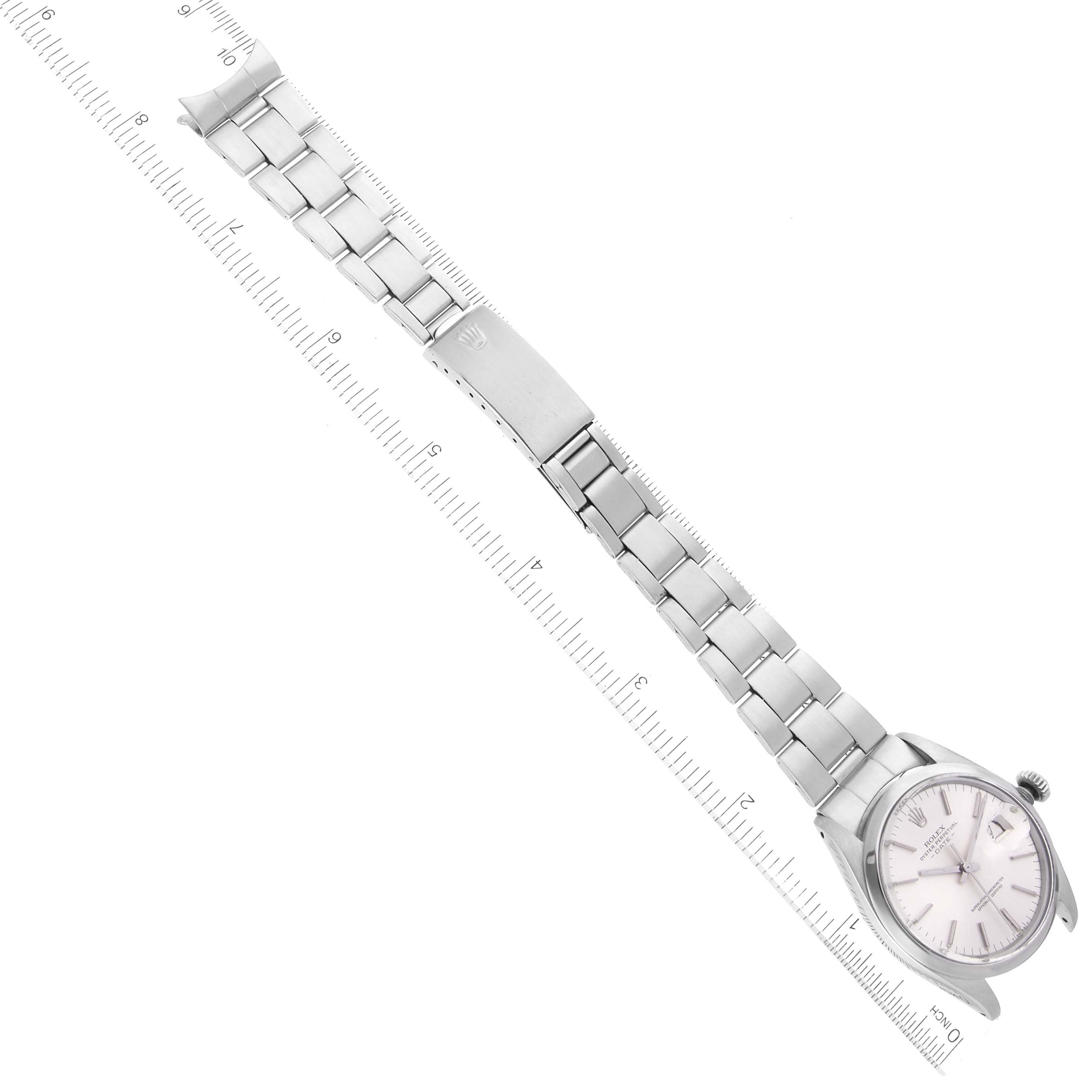 The Rolex Date 1500 Men's Stainless Steel Silver Dial model watch is shown from an angled top view, displaying the bracelet and clasp alongside a ruler for scale.
