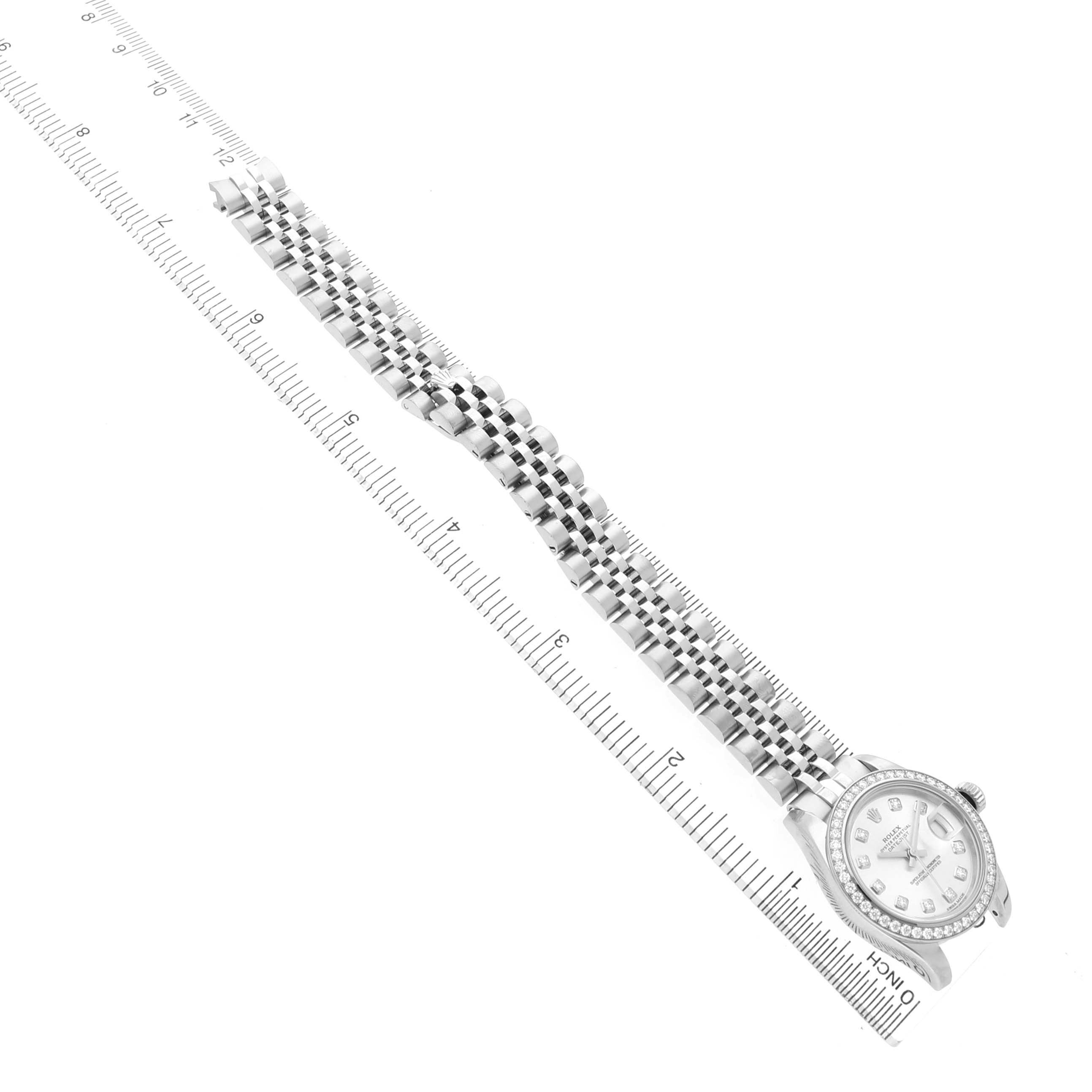The Rolex Datejust 179384 Women's Stainless Steel Silver Dial watch is shown at an angle displaying the entire bracelet and face, alongside a measuring scale.