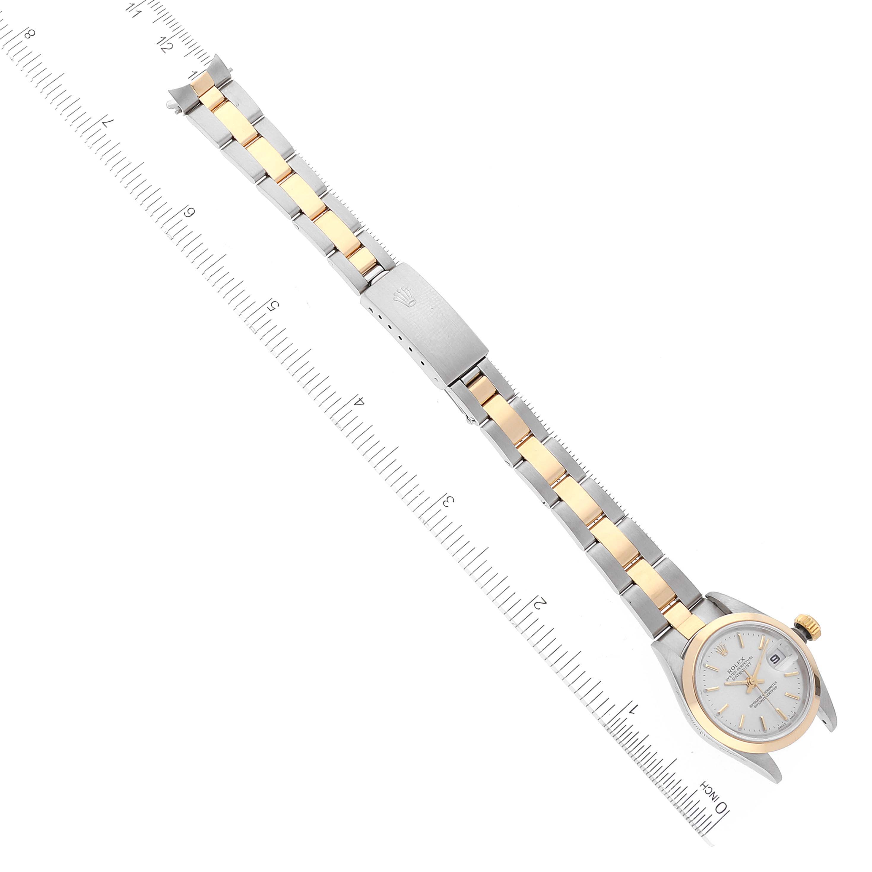 The image shows a Rolex Datejust 79163 Women's Steel and Gold (two tone) Silver Dial 79163 Women's Steel and Gold (two tone) Silver Dial watch laid flat on a ruler, displaying the face, case, bracelet, and clasp.