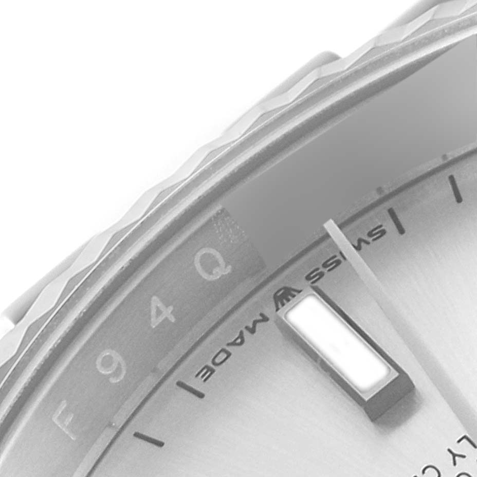 This close-up image of a Rolex Datejust 126234 Men's Stainless Steel Silver Dial 126234 Men's Stainless Steel Silver Dial watch shows part of the bezel, dial, and a hand.