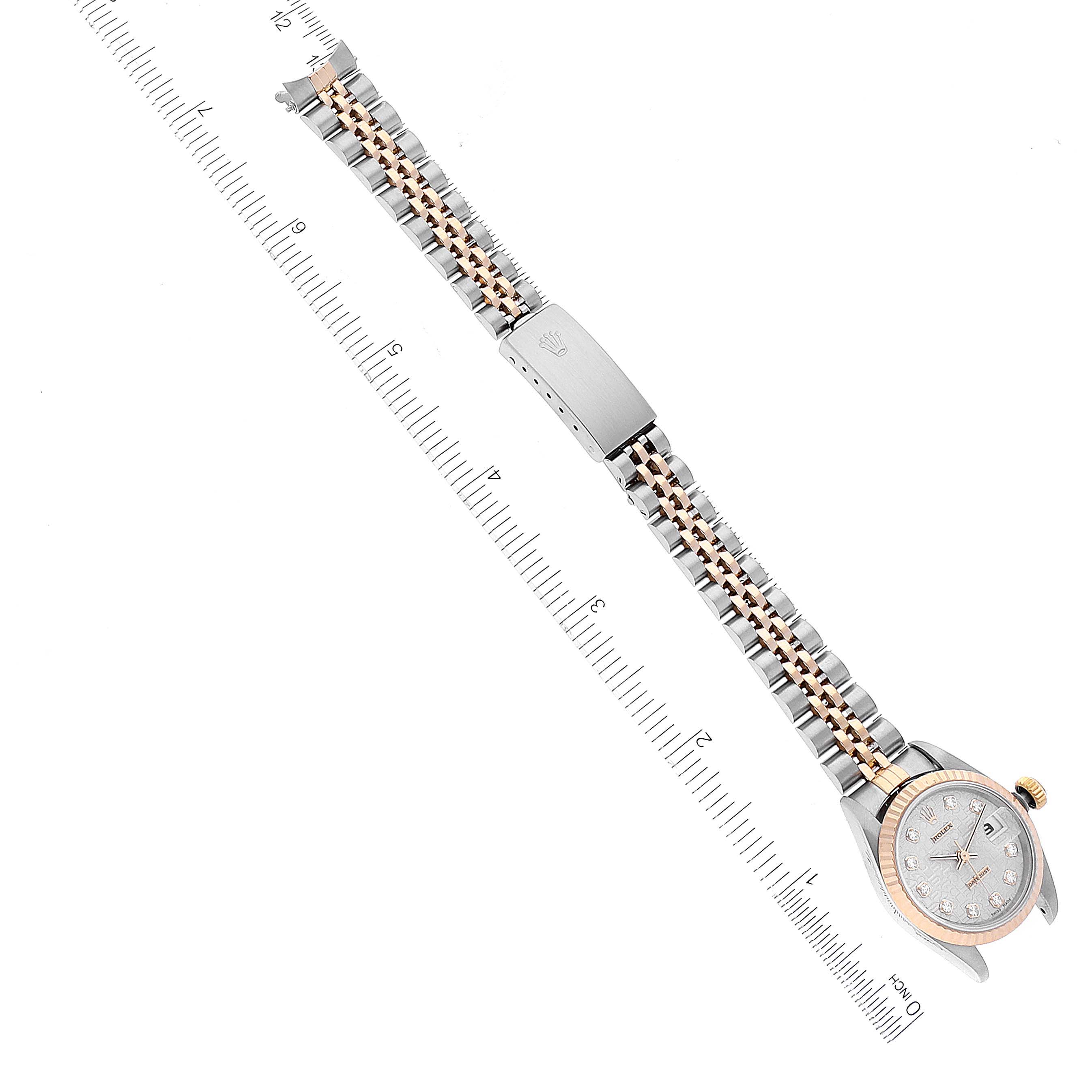 This overhead view shows the Rolex Datejust 69173 Women's Steel and Gold (two tone) Silver Dial 69173 Women's Steel and Gold (two tone) Silver Dial watch with its face, bezel, and jubilee bracelet displayed alongside a ruler for scale.