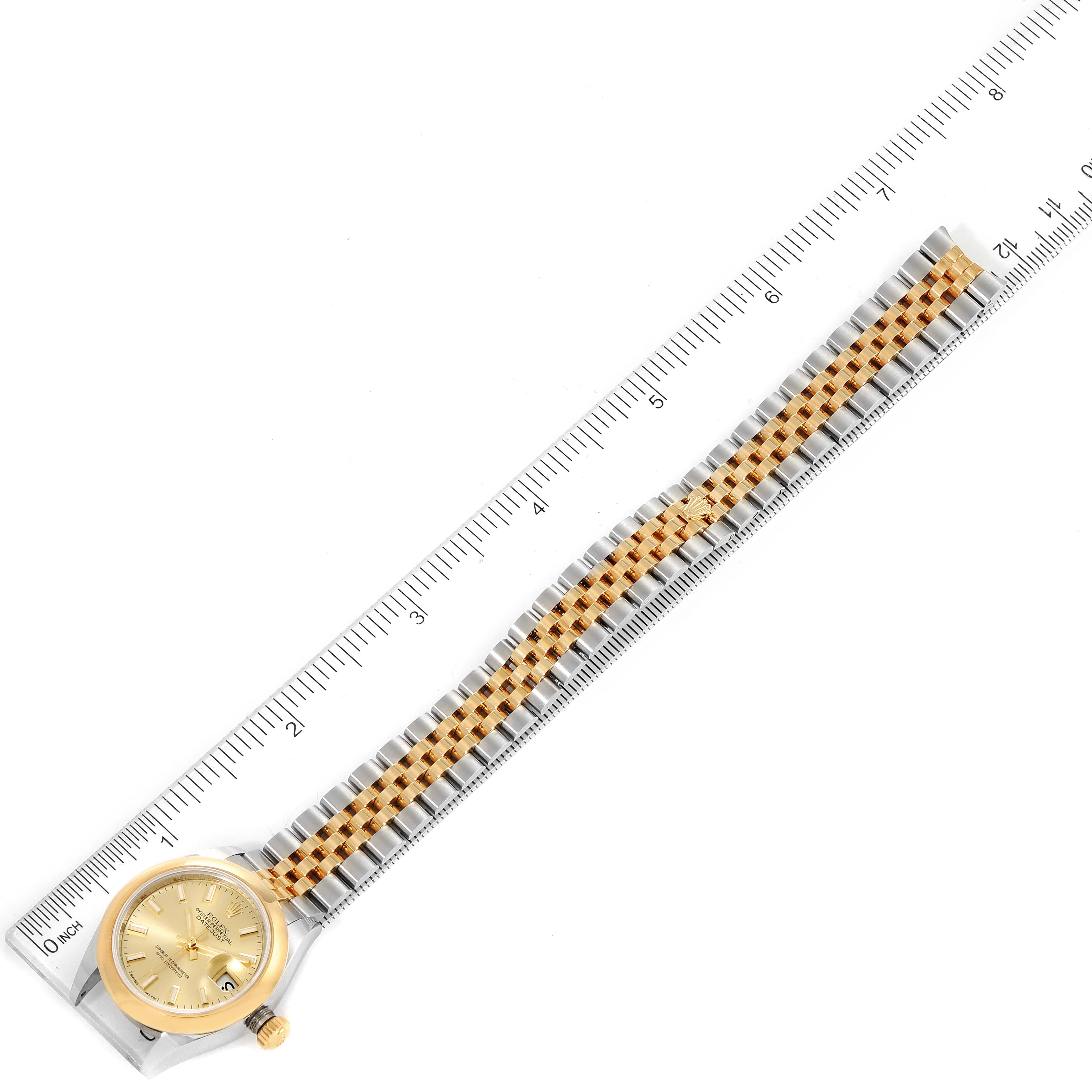 The Rolex Datejust 279163 Women
s Steel and Gold (two tone) Champagne Dial 279163 Women
s Steel and Gold (two tone) Champagne Dial watch is shown from an overhead view with a clear plastic ruler, displaying the full bracelet extended.