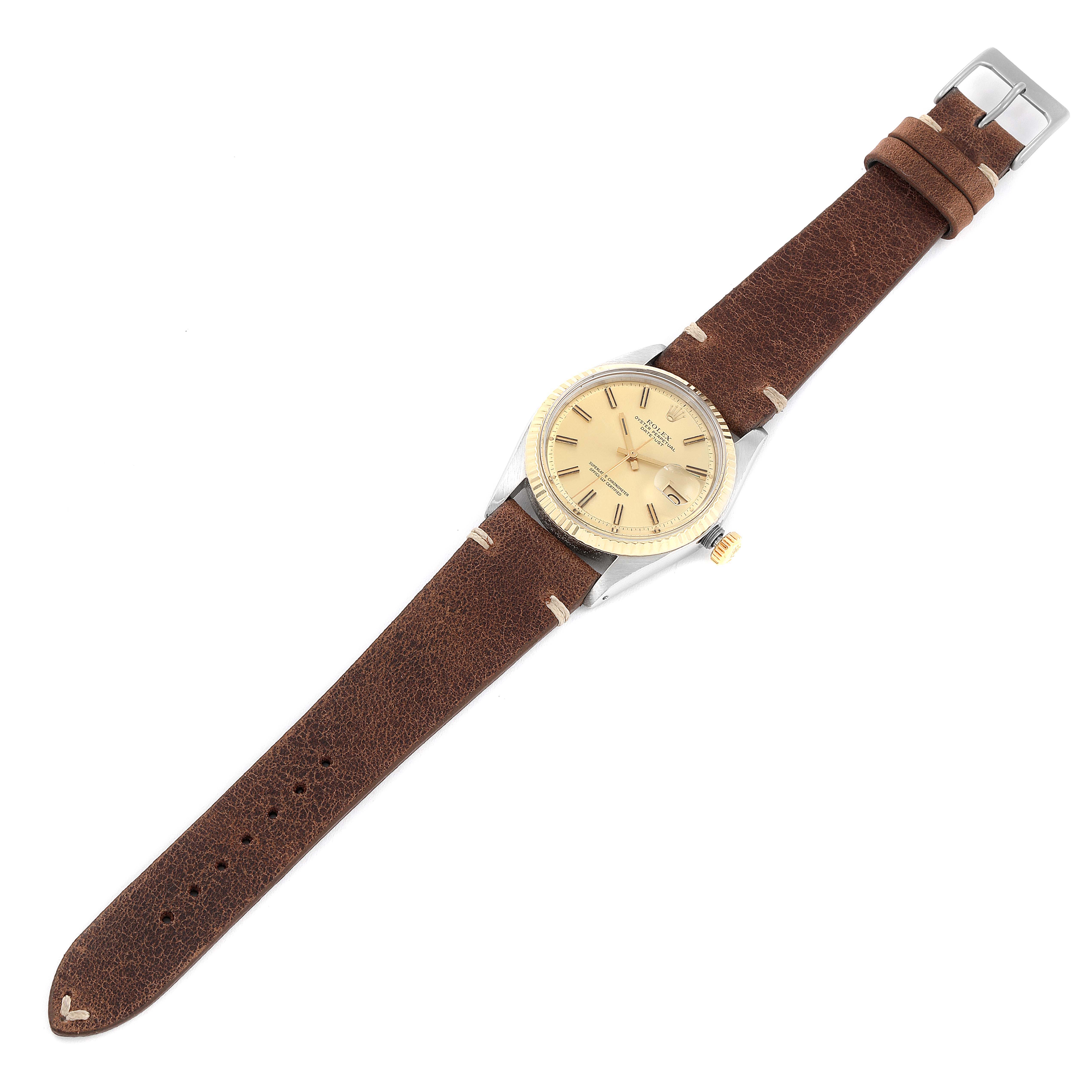 The Rolex Datejust 1601 Men
s Steel and Gold (two tone) Champagne Dial 1601 Men
s Steel and Gold (two tone) Champagne Dial watch is seen from a top-down angle, displaying its dial, bezel, case, and brown leather strap.