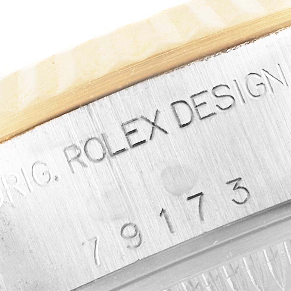The image shows an engraved serial number and "ROLEX DESIGN" text on the side of the Rolex Datejust 79173 Women
s Steel and Gold (two tone) Champagne Dial 79173 Women
s Steel and Gold (two tone) Champagne Dial watch case.
