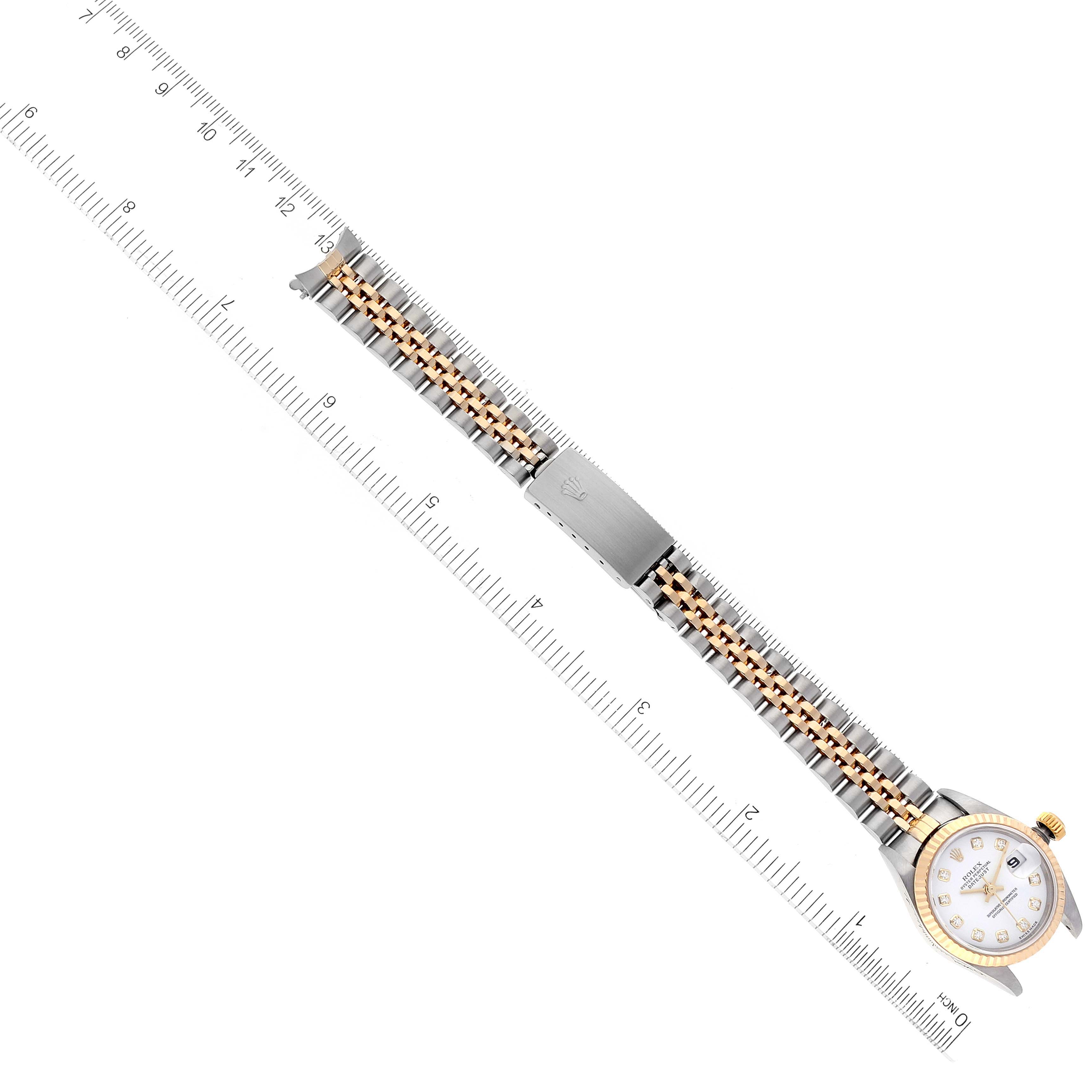 This image shows a Rolex Datejust 79173 Women
s Steel and Gold (two tone) White Dial 79173 Women
s Steel and Gold (two tone) White Dial watch laid flat, highlighting the band and dial beside a measuring ruler.