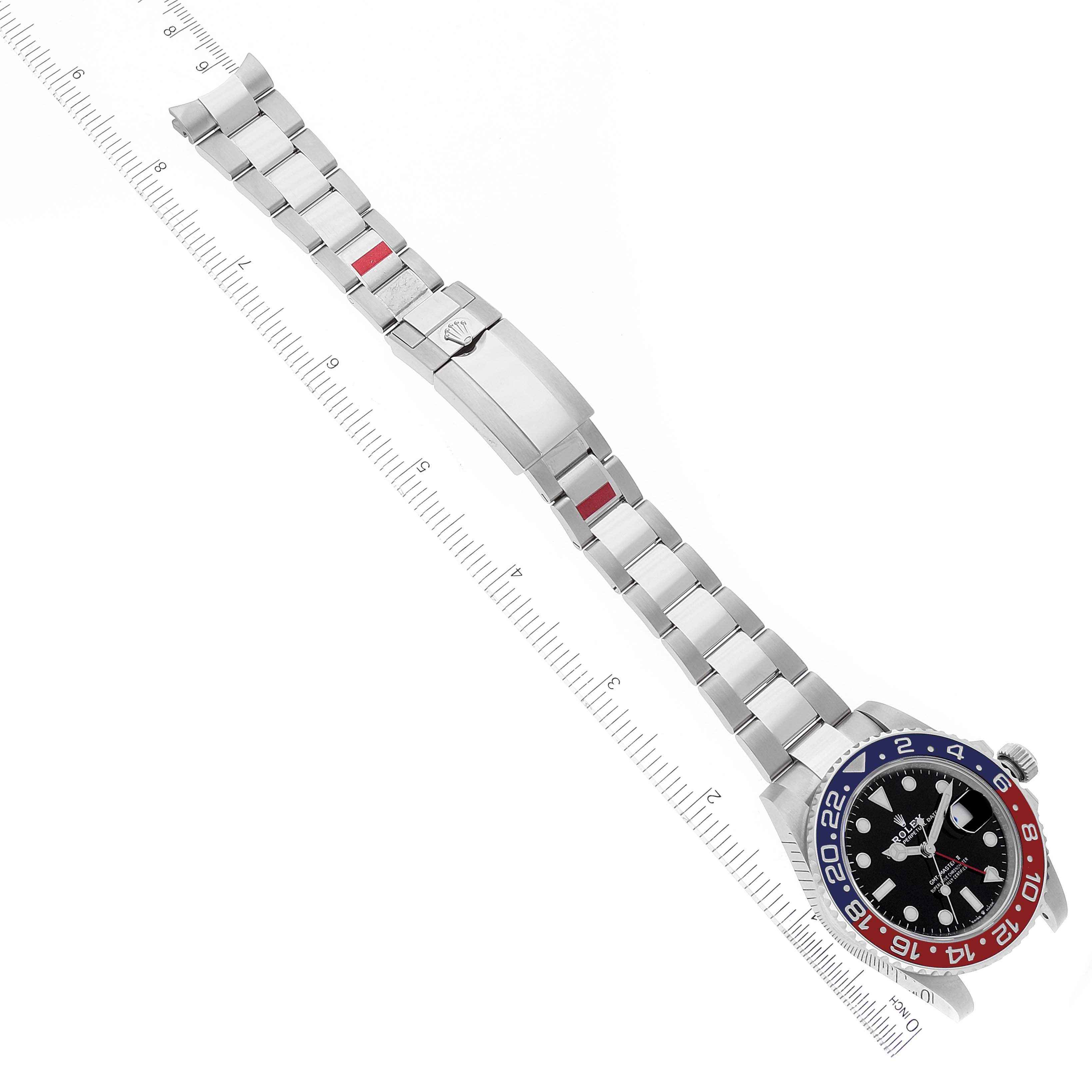 This image shows a Rolex GMT-Master 126710 Men's Stainless Steel Black Dial 126710 Men's Stainless Steel Black Dial watch laying flat with its bracelet extended and a ruler for scale.